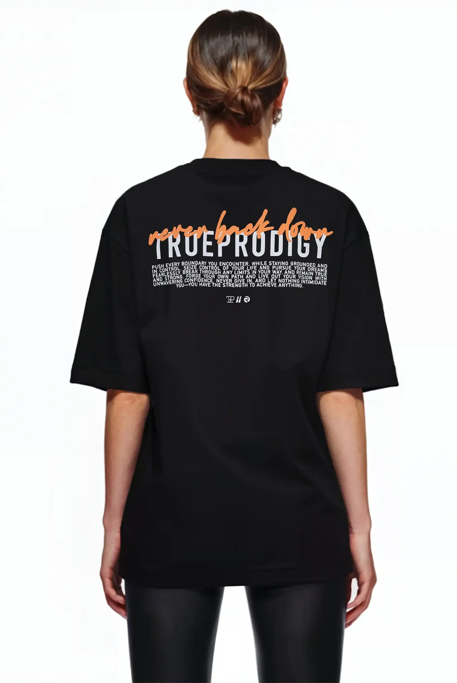 Eine Person mit braunen Haaren in einem tiefen Dutt trägt das trueprodigy Lior F Oversize-Damen-T-Shirt mit der Aufschrift "never back down" auf dem Rücken. Sie kombiniert es mit einer schwarzen Hose und steht vor einem weißen Hintergrund.