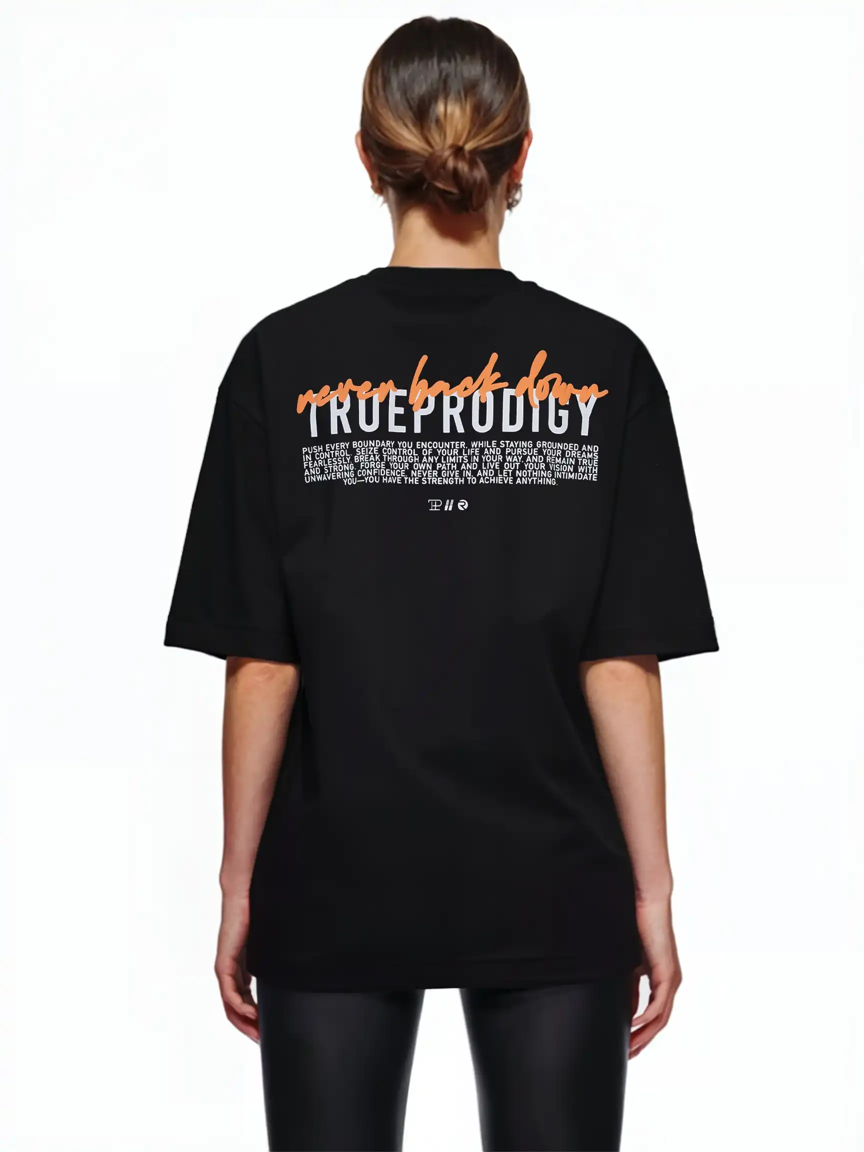 Eine Person mit braunen Haaren in einem tiefen Dutt trägt das trueprodigy Lior F Oversize-Damen-T-Shirt mit der Aufschrift "never back down" auf dem Rücken. Sie kombiniert es mit einer schwarzen Hose und steht vor einem weißen Hintergrund.