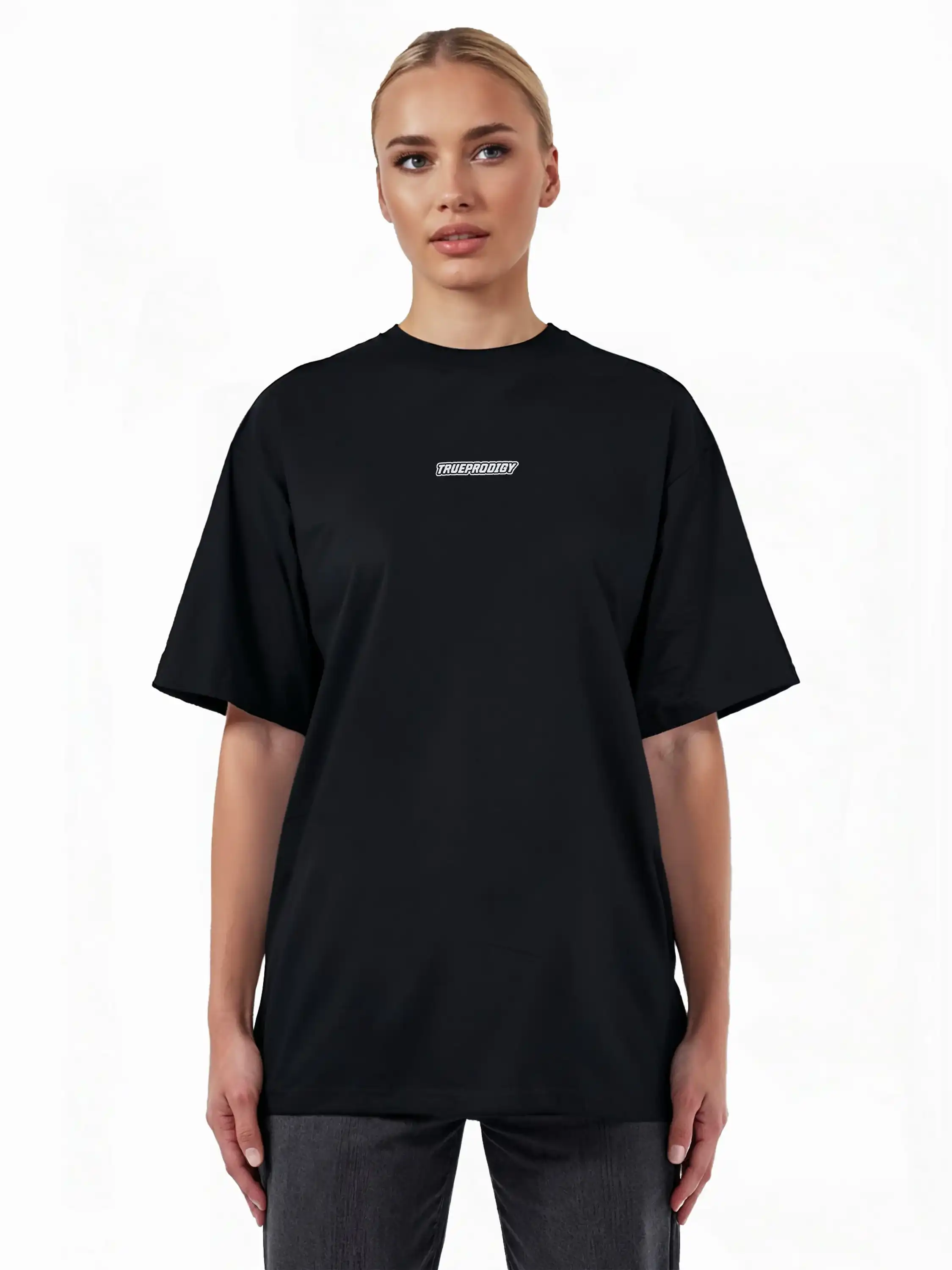 Eine Person steht mit dem Blick nach vorne und trägt das trueprodigy Eden F Oversize-T-Shirt mit 3D-Logo-Schriftzug vorn & großem Rückenprint in schwarz mit kurzen Ärmeln, gepaart mit einer dunklen Hose, vor einem weißen Hintergrund.
