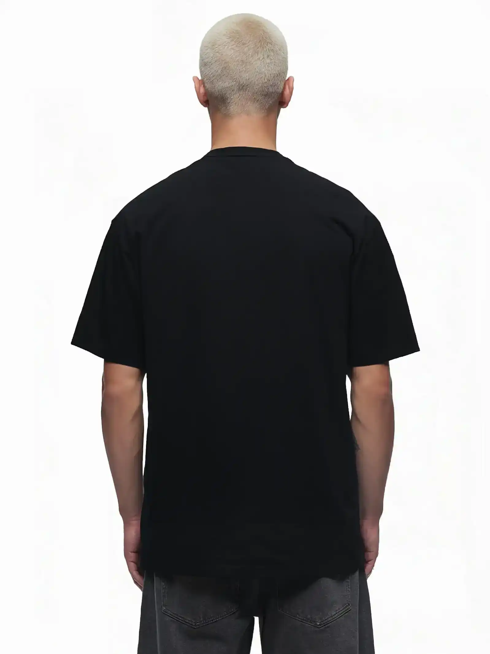 Eine Person mit kurzen, hellblonden Haaren steht mit dem Rücken zur Kamera und trägt ein Trueprodigy Haram Oversize-Herren-T-Shirt mit dezentem TPDY-Sticklogo und dunkelgraue Jeans vor einem weißen Hintergrund.
