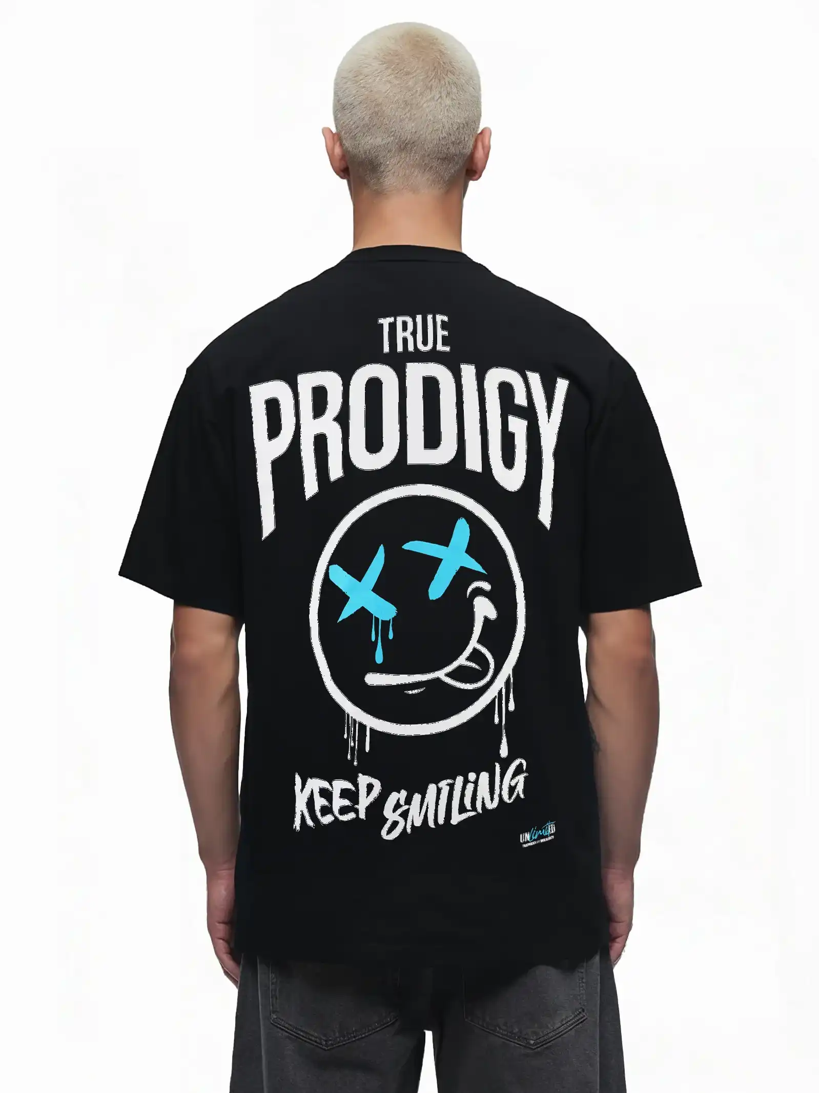 Eine Person mit kurzen, hellen Haaren ist von hinten zu sehen. Sie trägt das trueprodigy Kenji Oversize-T-Shirt mit einem auffälligen weiß-blauen Smiley-Gesicht und dem Text "TRUE PRODIGY KEEP SMILING" als großen Rückenaufdruck.