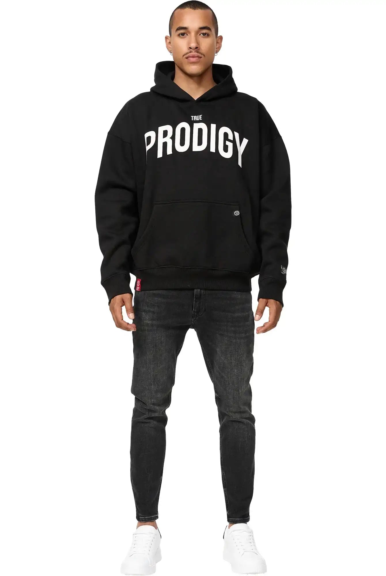 Ein Mann steht mit dem Gesicht nach vorne und trägt einen trueprodigy Tobi Oversized Hoodie mit Print, schwarze Jeans und weiße Turnschuhe vor einem schlichten weißen Hintergrund.