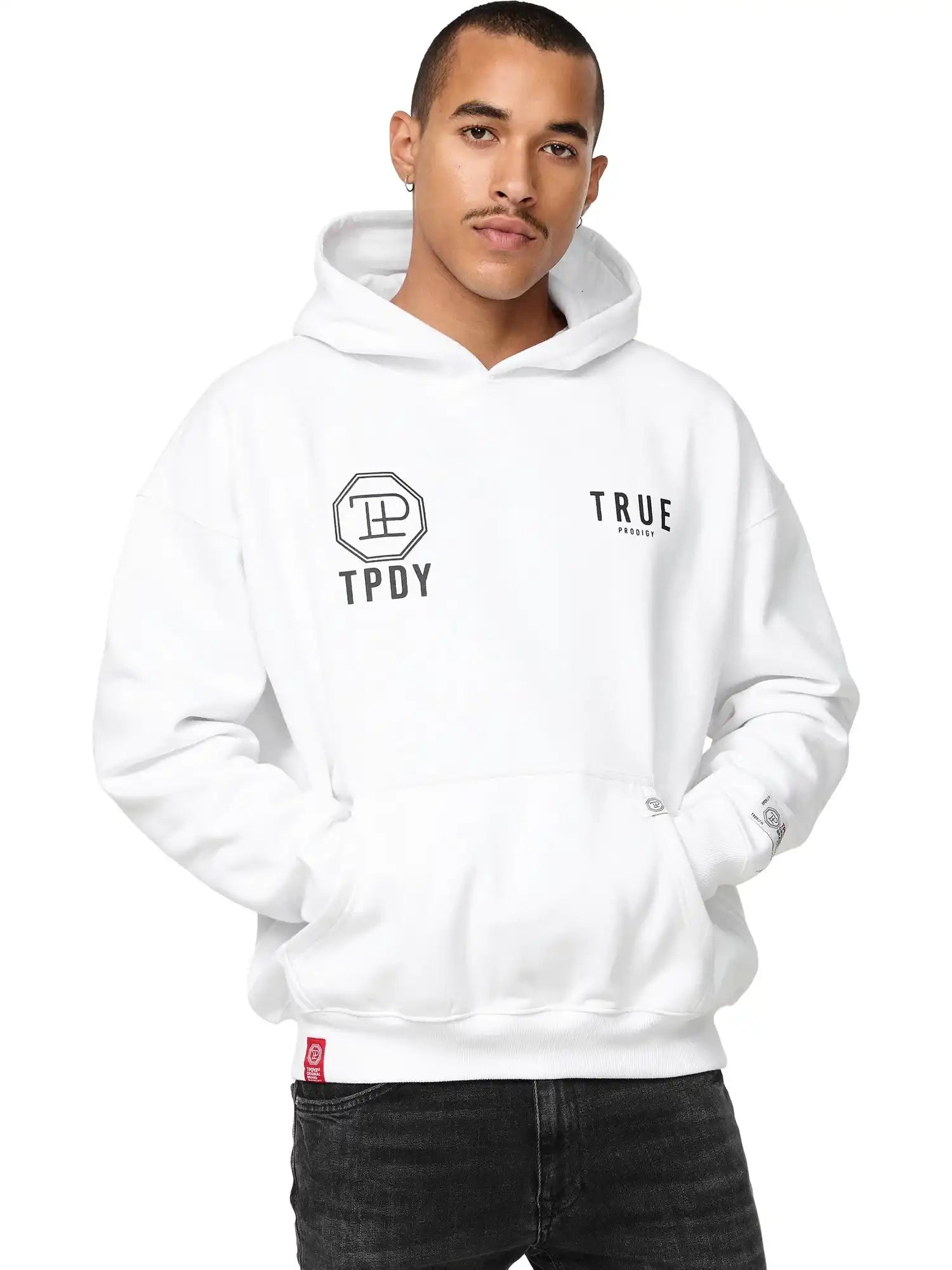 Eine Person mit kurzen Haaren und schwarzen Jeans trägt den trueprodigy Aaren Oversized Hoodie mit Print, mit TPDY und trueprodigy Logos auf der Vorderseite, gestylt mit einer Hand in der Tasche.