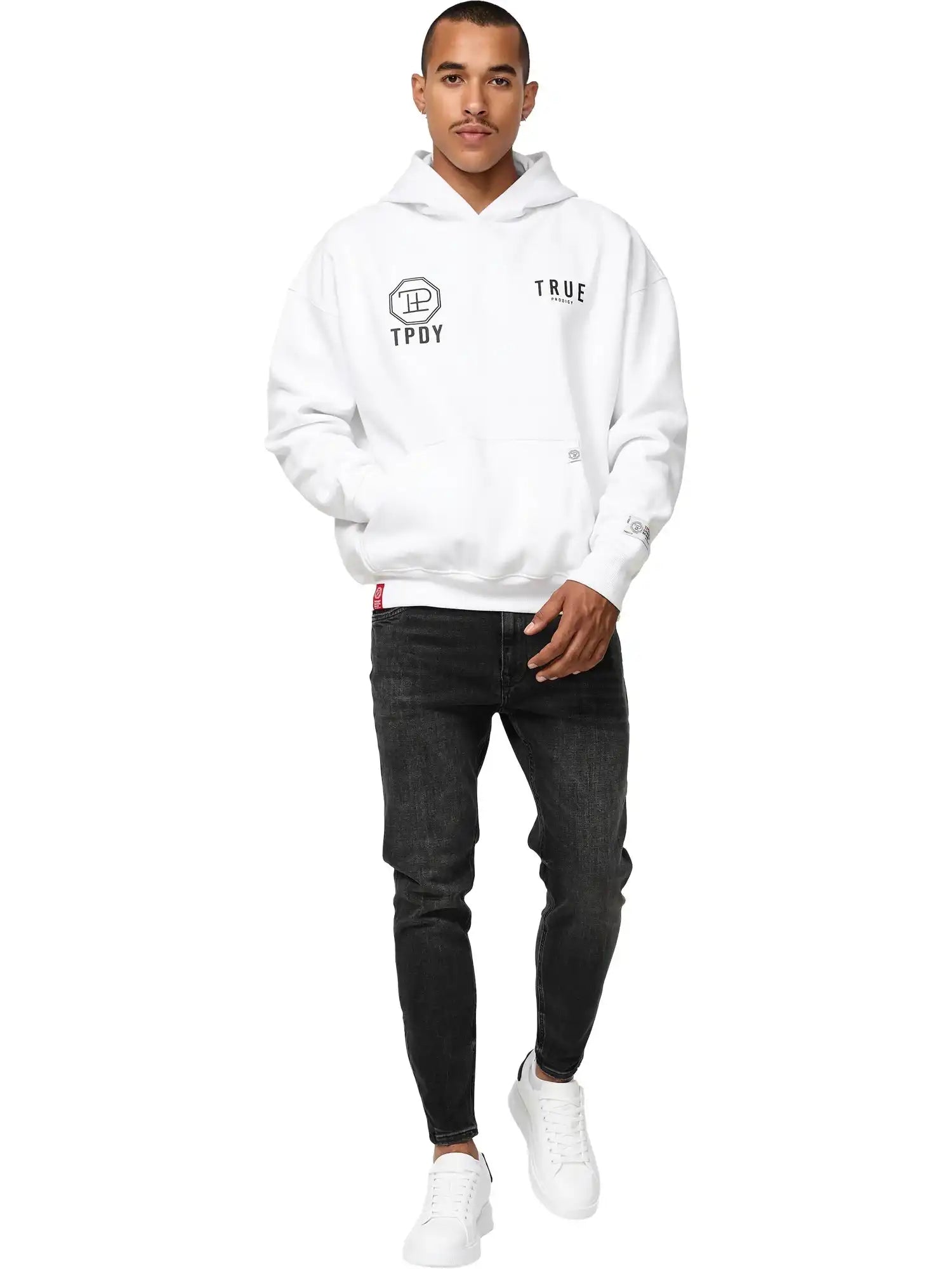 Ein Mann sieht nach vorne und trägt einen weißen trueprodigy Aaren Oversized Hoodie mit Print, schwarze Skinny Jeans und weiße Turnschuhe vor einem schlichten weißen Hintergrund.