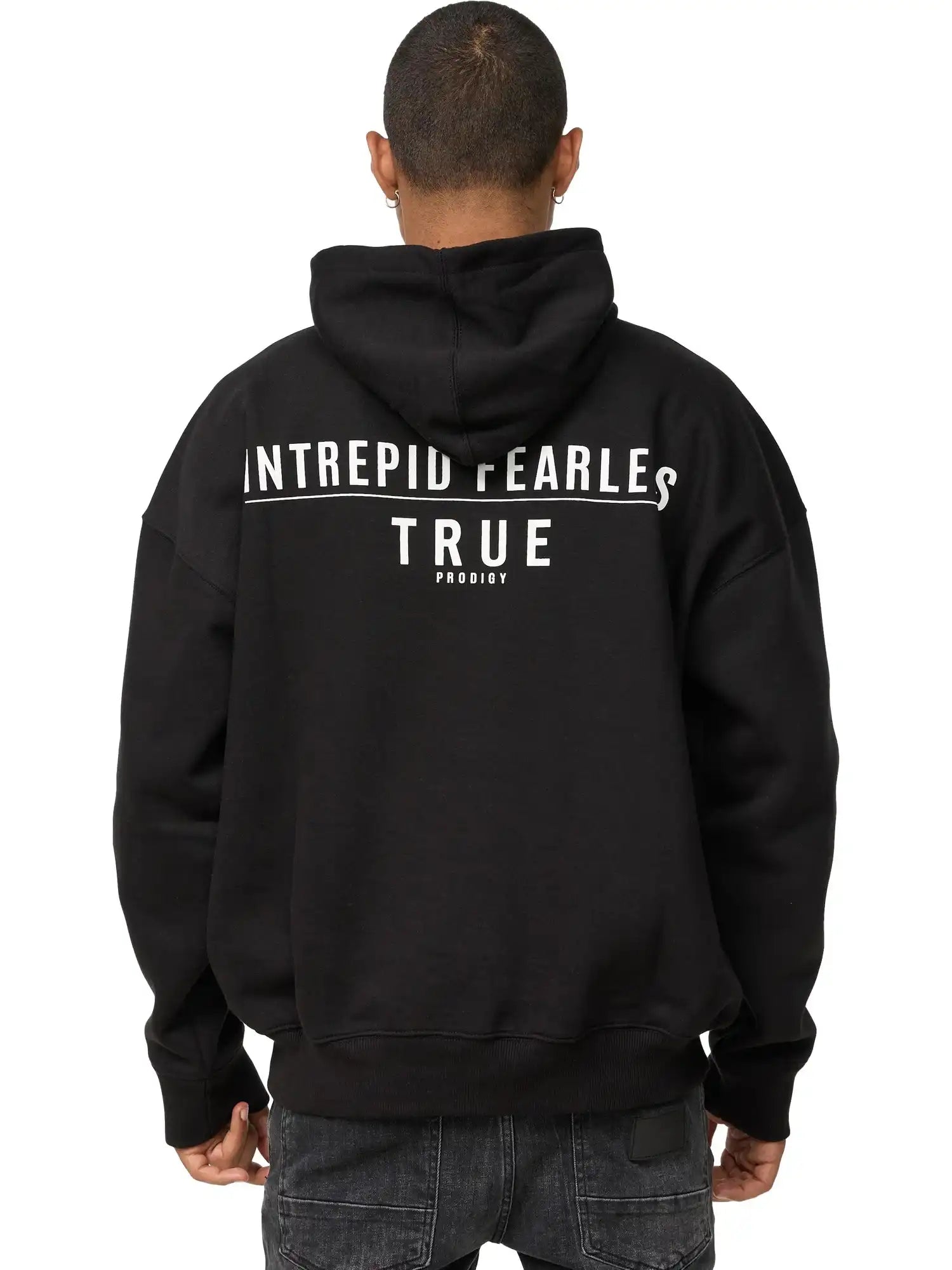 Eine Person, die den trueprodigy Aaren Oversized Hoodie mit Print in schwarz mit der Aufschrift "INTREPID FEARLESS TRUE PRODIGY" in weiß auf dem Rücken trägt, steht mit dem Rücken zur Kamera. Dieser Kapuzenpulli setzt ein mutiges Statement.