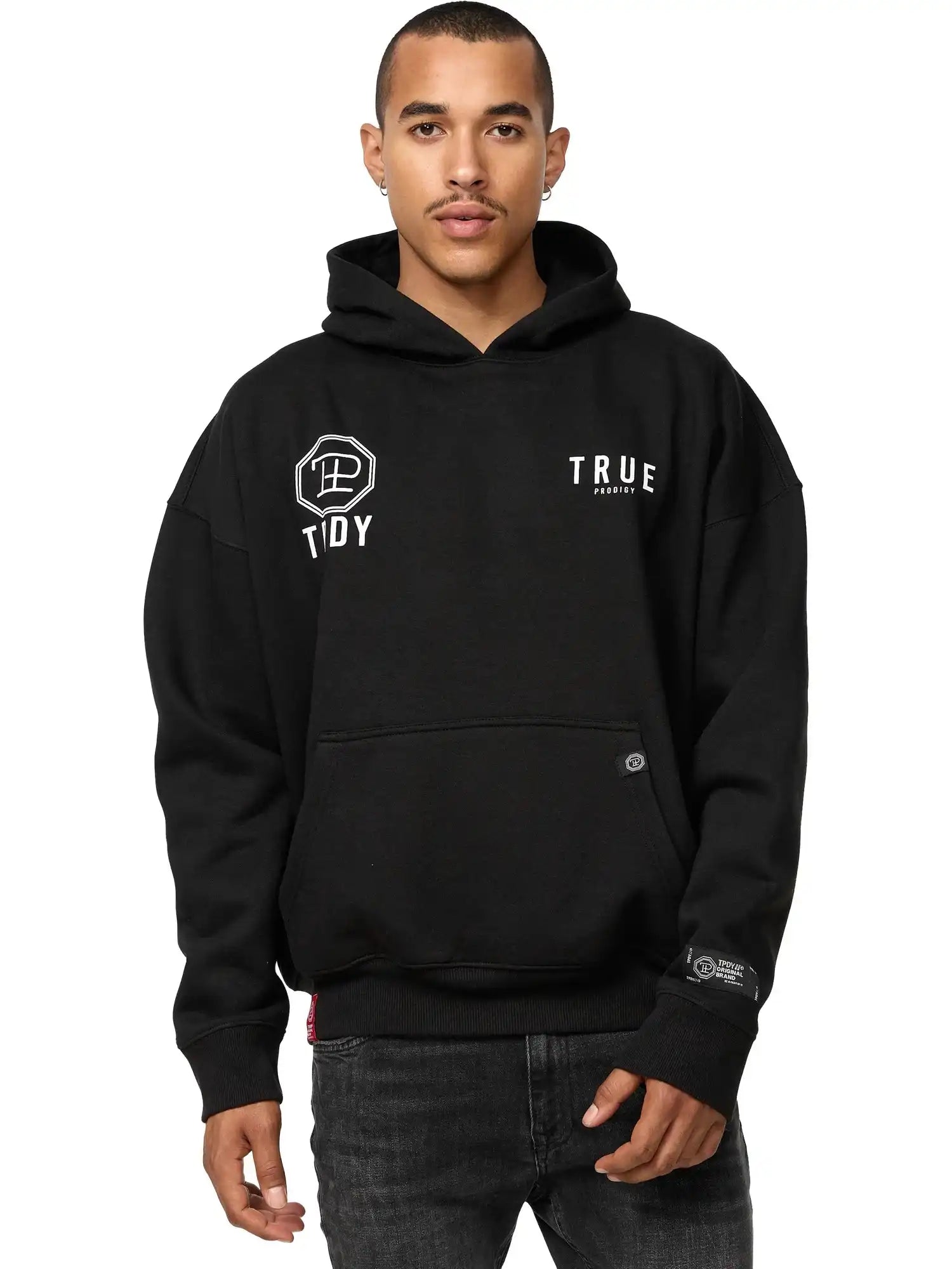 Eine Person steht mit Blick nach vorne in einem schwarzen, übergroßen trueprodigy Aaren Hoodie mit Print mit Fronttasche und weißem Logo, gepaart mit einer schwarzen Jeans vor einem schlichten weißen Hintergrund.