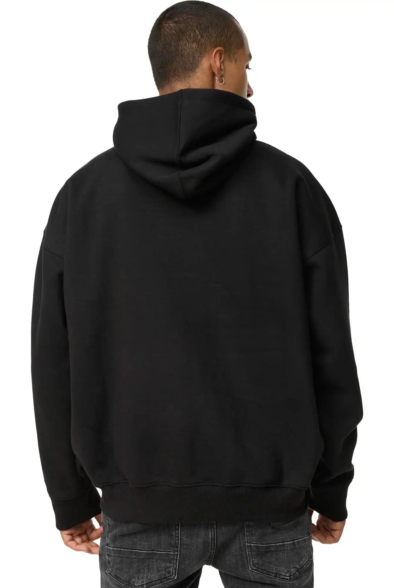 Eine Person mit kurzen Haaren ist von hinten zu sehen. Sie trägt einen trueprodigy Janne Oversized Hoodie mit Print und dunkle Jeans vor einem schlichten weißen Hintergrund.