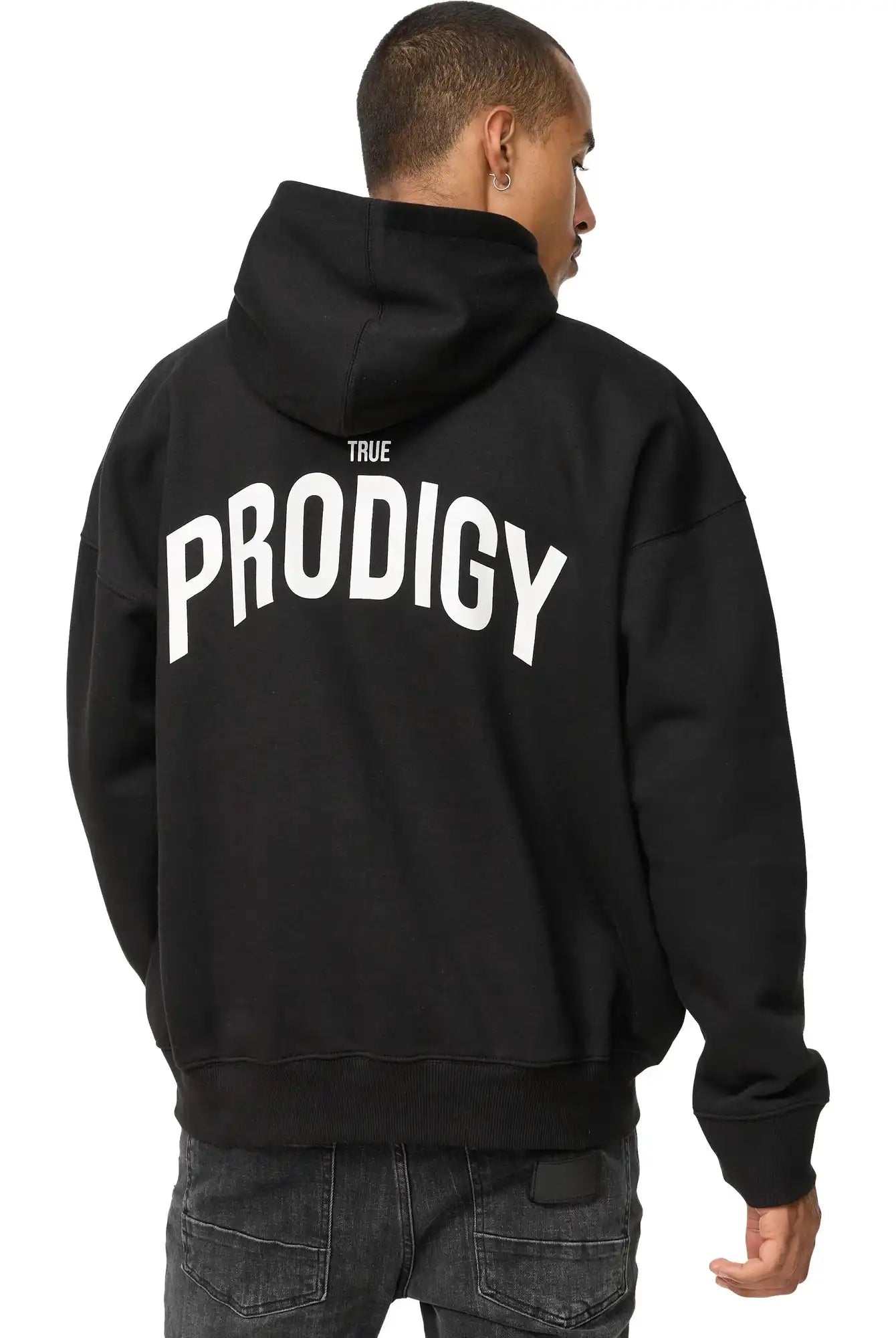 Eine Person in einem schwarzen trueprodigy Quinn Oversized Hoodie mit Print, mit fettem TRUE PRODIGY Schriftzug auf dem Rücken, steht mit dem Rücken zur Kamera.
