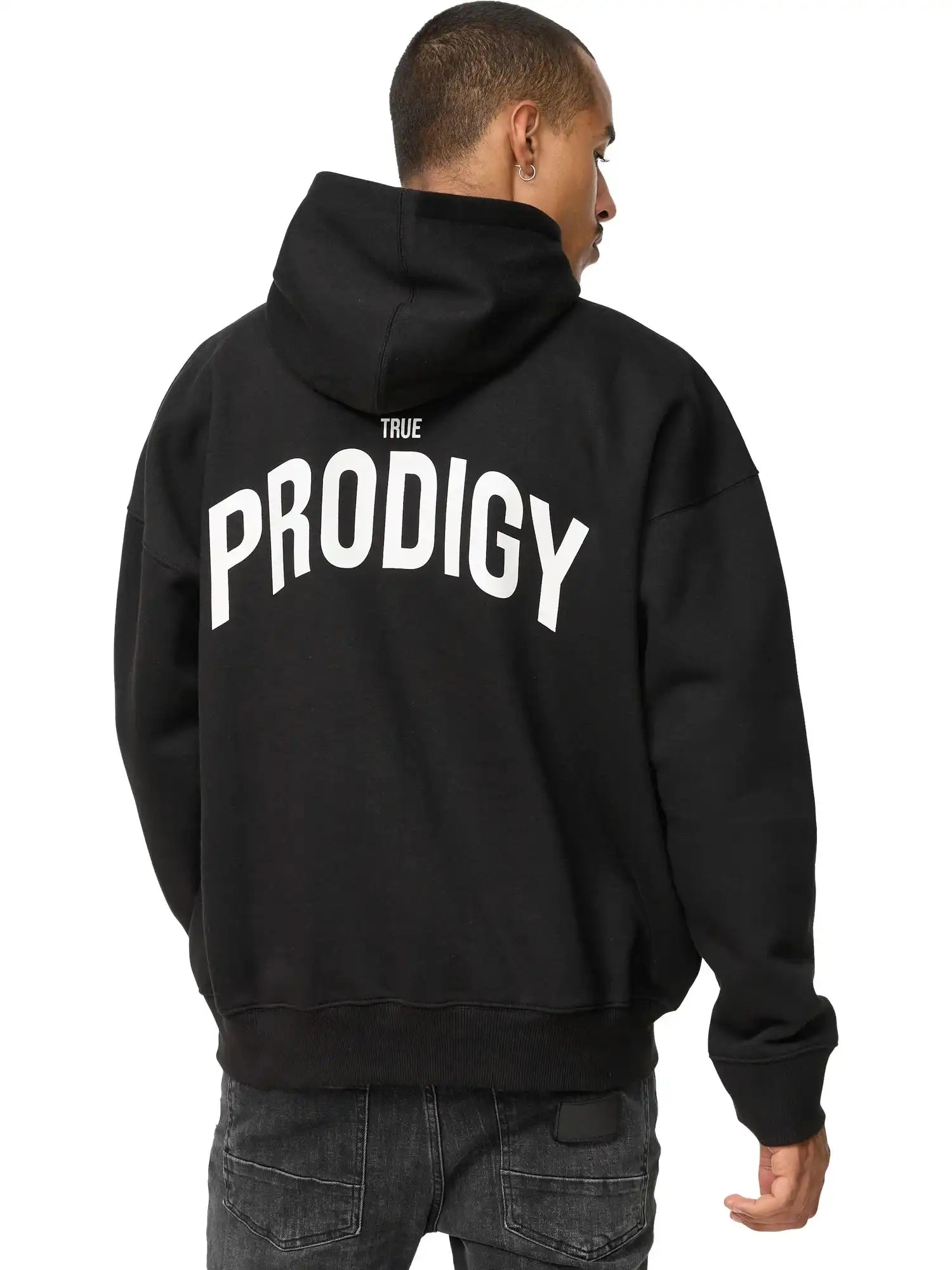Eine Person in einem schwarzen trueprodigy Quinn Oversized Hoodie mit Print, mit fettem TRUE PRODIGY Schriftzug auf dem Rücken, steht mit dem Rücken zur Kamera.