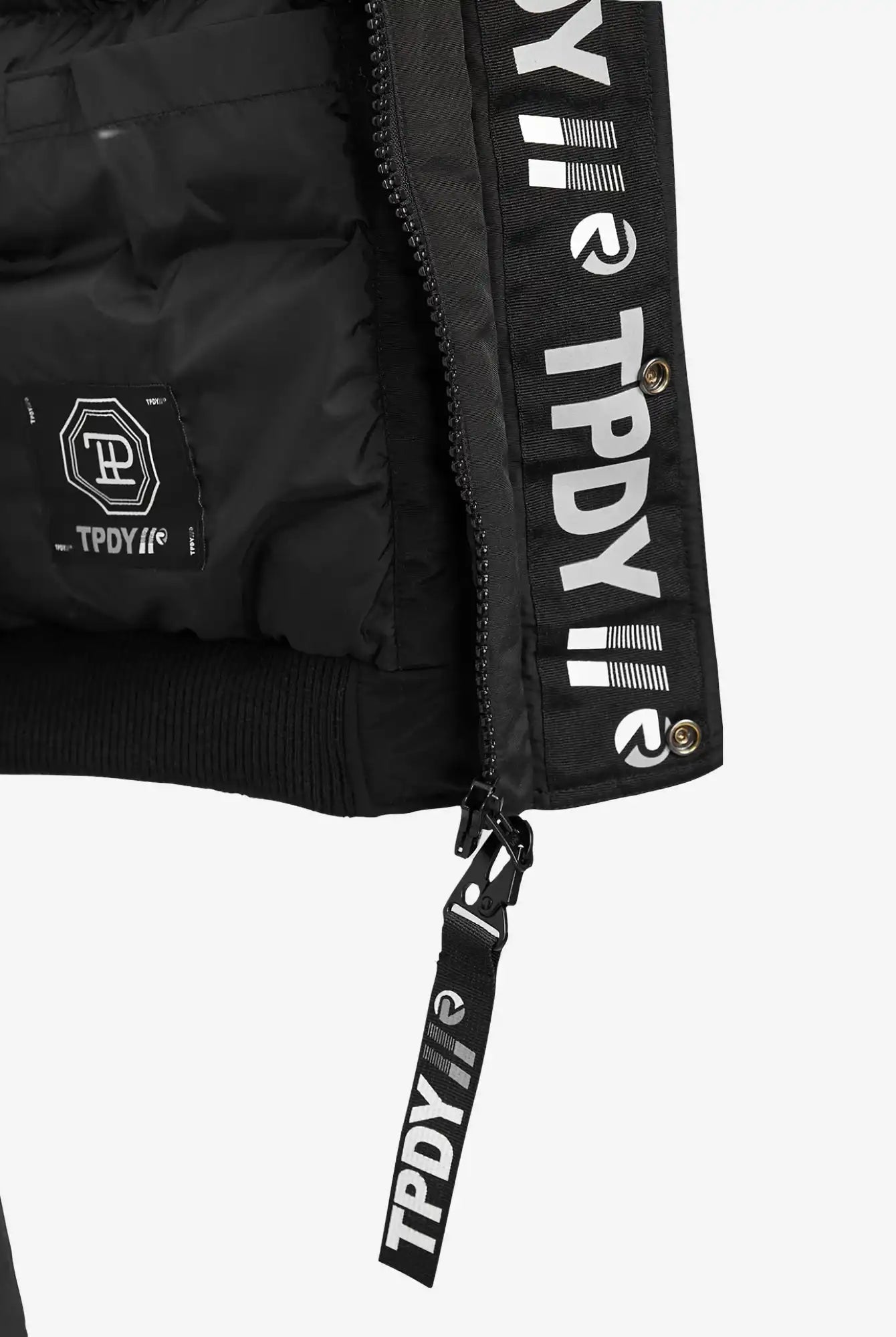 Nahaufnahme des schwarzen trueprodigy Noah Winterparka mit Kapuze und Kunstfell, mit eingebranntem "TPDY"-Schriftzug und Logodetails auf dem Reißverschluss, dem Innenetikett und der Innenkante. Weißer Schriftzug kontrastiert mit schwarzem Stoff; abnehmbare Kapuze für Vielseitigkeit.