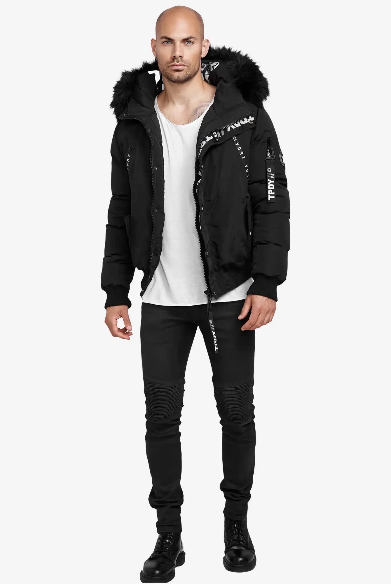 Ein Mann steht vor einem weißen Hintergrund und trägt die Trueprodigy Noah Winterparka mit Kapuze und Kunstfell, ein weißes T-Shirt, schwarze Jeans und schwarze Stiefel. Er blickt mit neutraler Miene nach vorne.