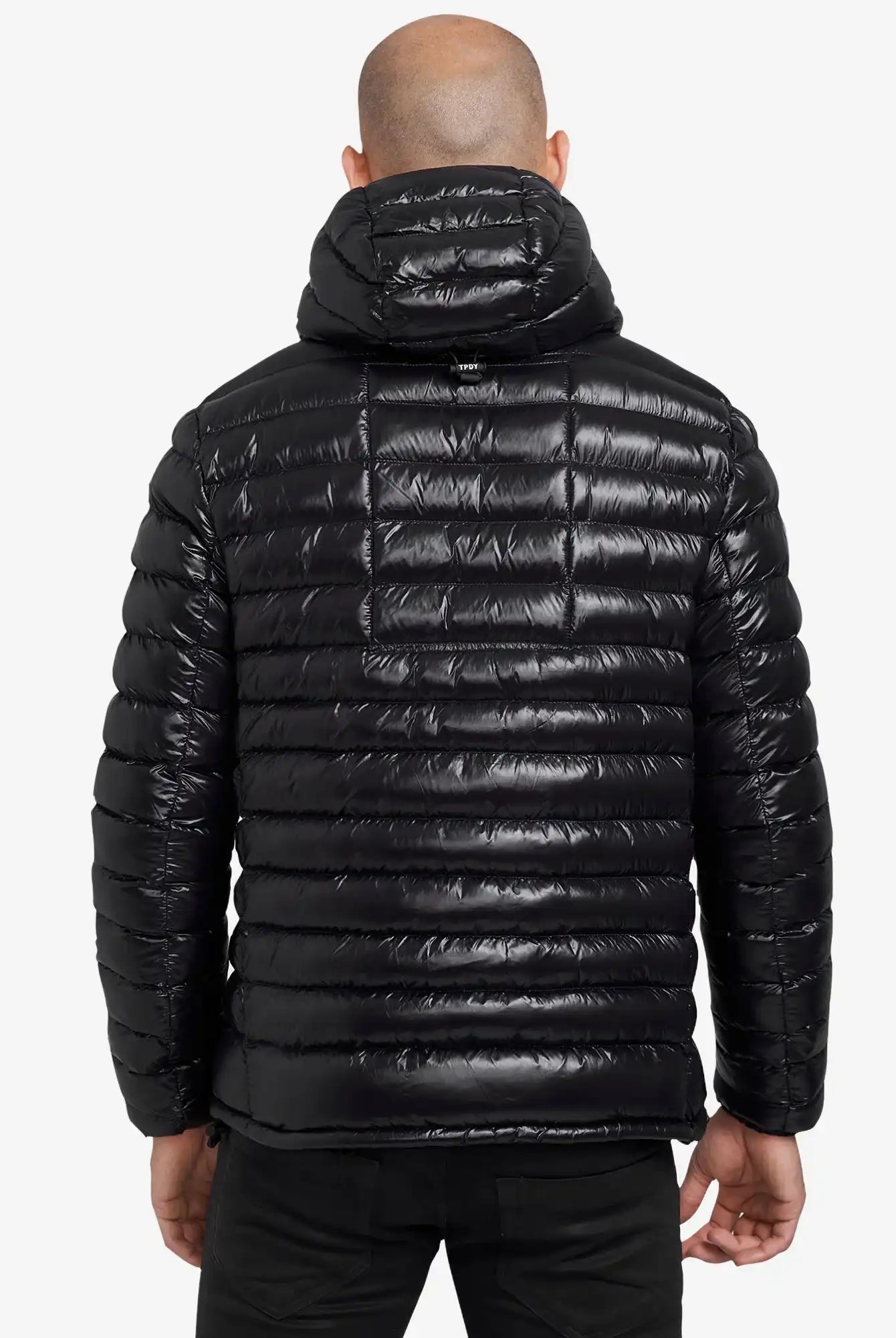 Von hinten ist eine Person mit Glatze zu sehen, die eine glänzende schwarze Trueprodigy Adan Steppjacke mit Kapuze mit horizontaler Steppung trägt. Die wasserabweisende Jacke hebt sich von dem schlichten weißen Hintergrund ab.