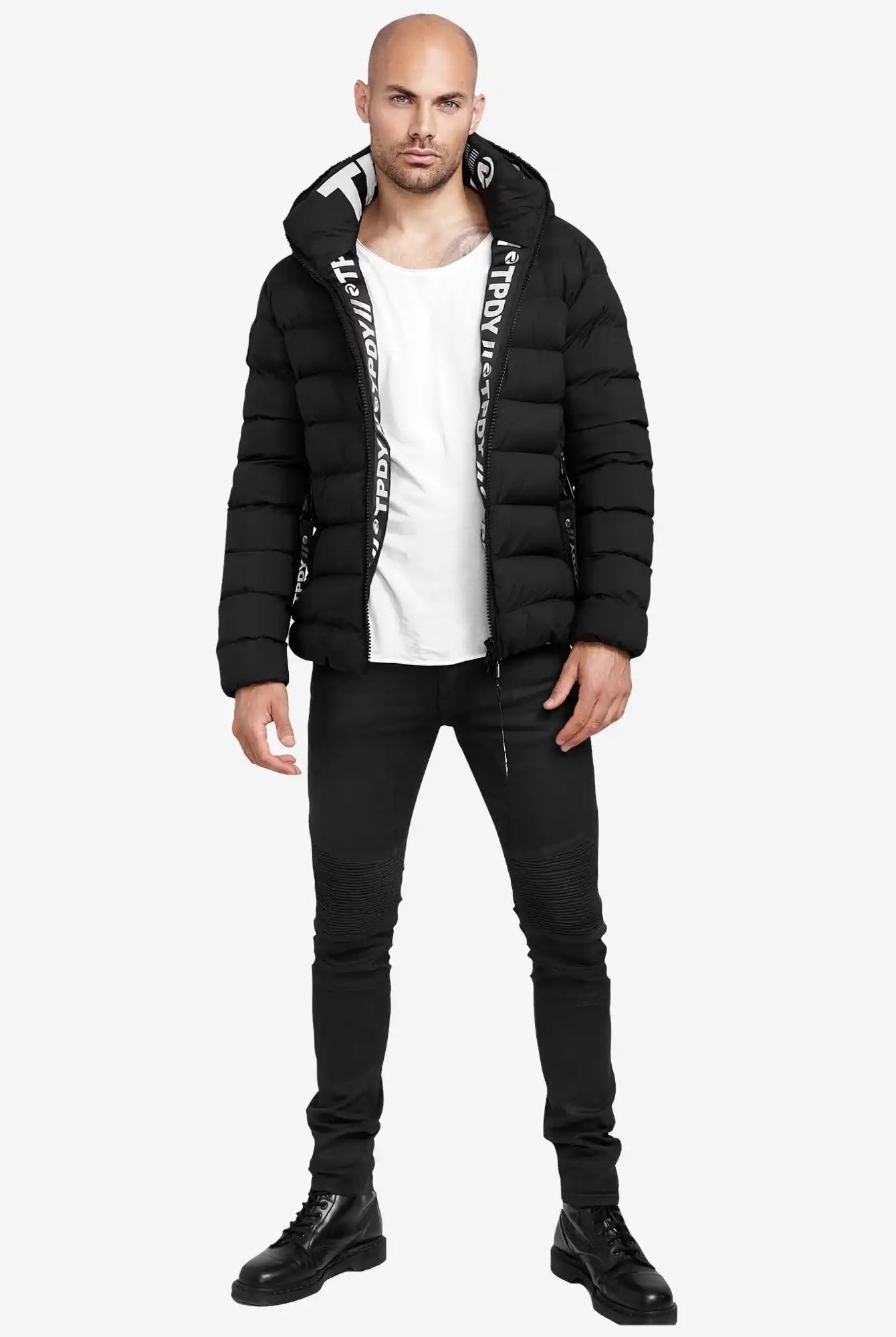 Eine Person steht vor einem schlichten weißen Hintergrund und trägt die trueprodigy Neo Kurze Pufferjacke mit Logo, ein weißes T-Shirt, schwarze Skinny Jeans und schwarze Schnürstiefel.