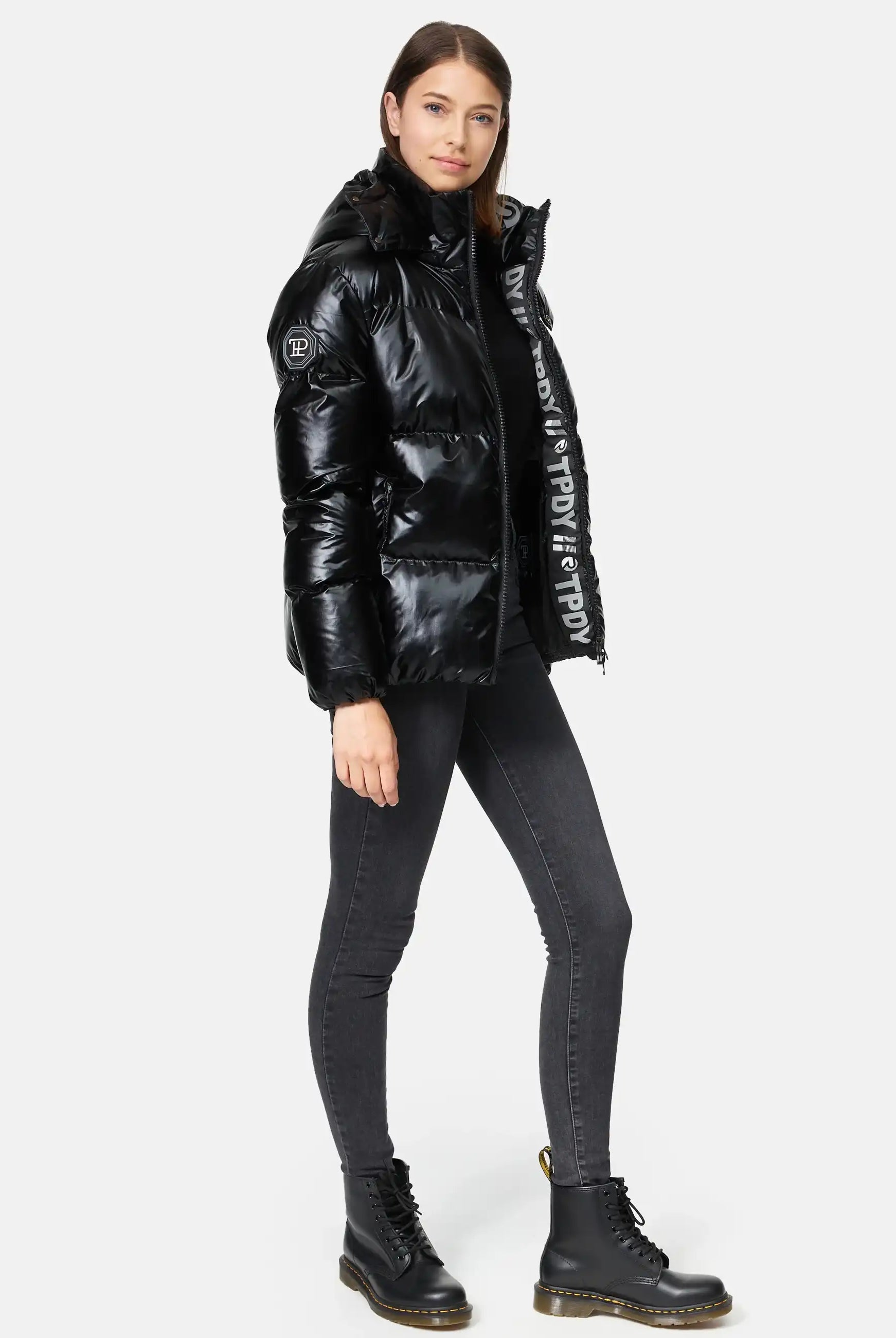 TRUEPRODIGY constance schwarze glänzende Pufferjacke, hohe Kapuze, seitliche Reißverschlusstaschen, modelliert von Frau, sorgt für stilvolles Winteroutfit; Design-Details unterstreichen modernen, urbanen Look.