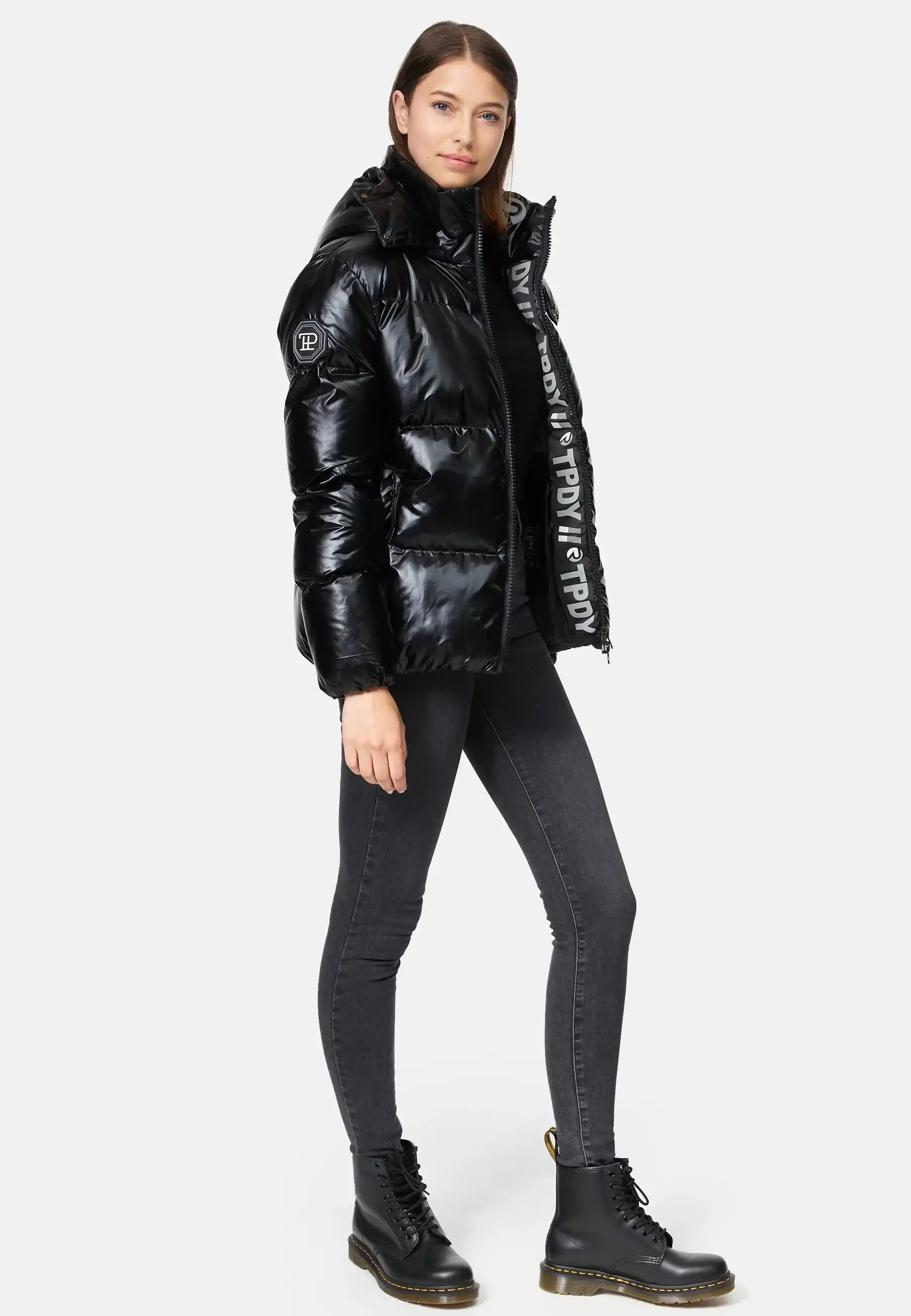 TRUEPRODIGY constance schwarze glänzende Pufferjacke, hohe Kapuze, seitliche Reißverschlusstaschen, modelliert von Frau, sorgt für stilvolles Winteroutfit; Design-Details unterstreichen modernen, urbanen Look.