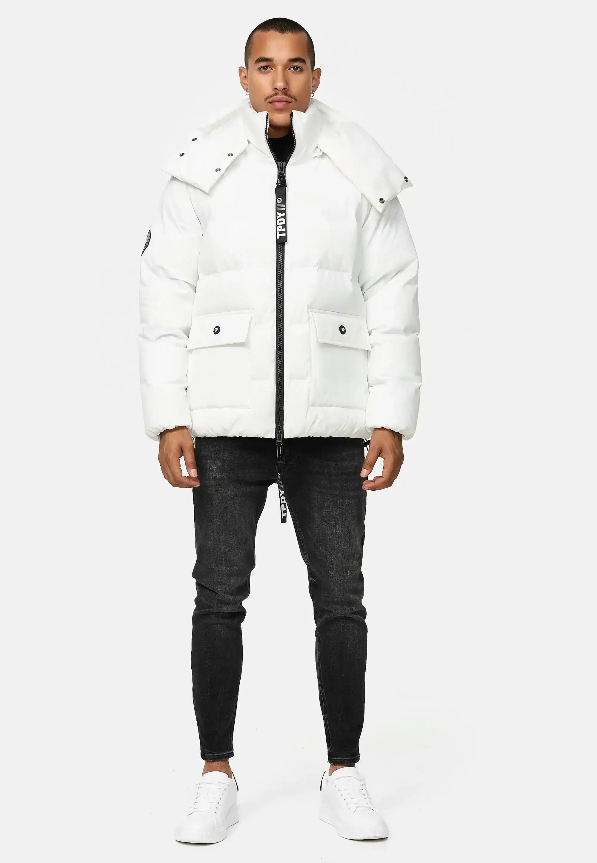 Ein Mann steht vor einem hellgrauen Hintergrund. Er trägt die trueprodigy Franco Winterjacke mit abnehmbarer Kapuze, schwarze Skinny Jeans und weiße Turnschuhe.