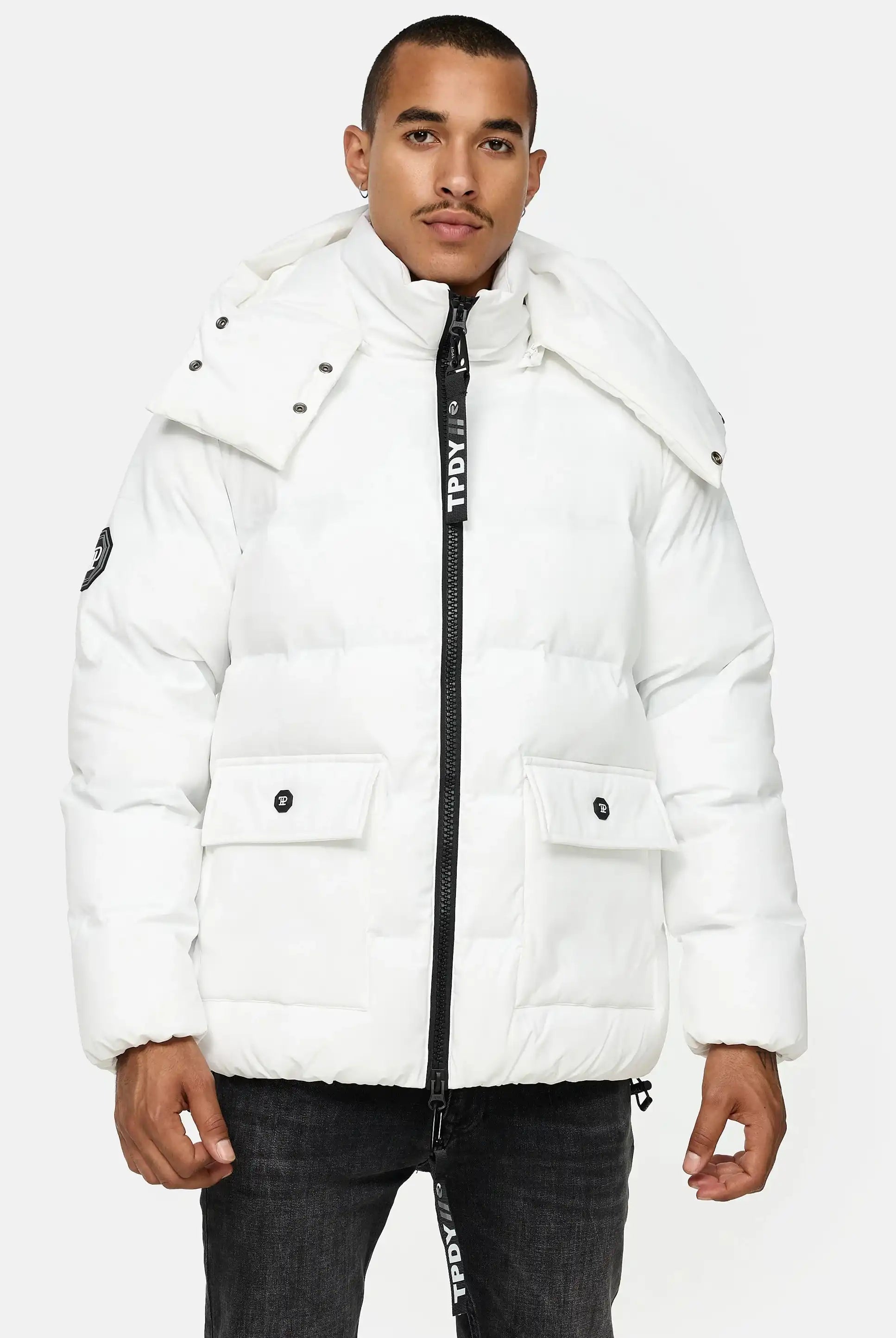 Ein Mann mit kurzen Haaren und neutralem Gesichtsausdruck trägt die trueprodigy Franco Winterjacke mit abnehmbarer Kapuze in Weiß, die sich durch ein reflektierendes Design, hohe Kragen, schwarzen Reißverschluss und große Fronttaschen vor hellem Hintergrund auszeichnet.