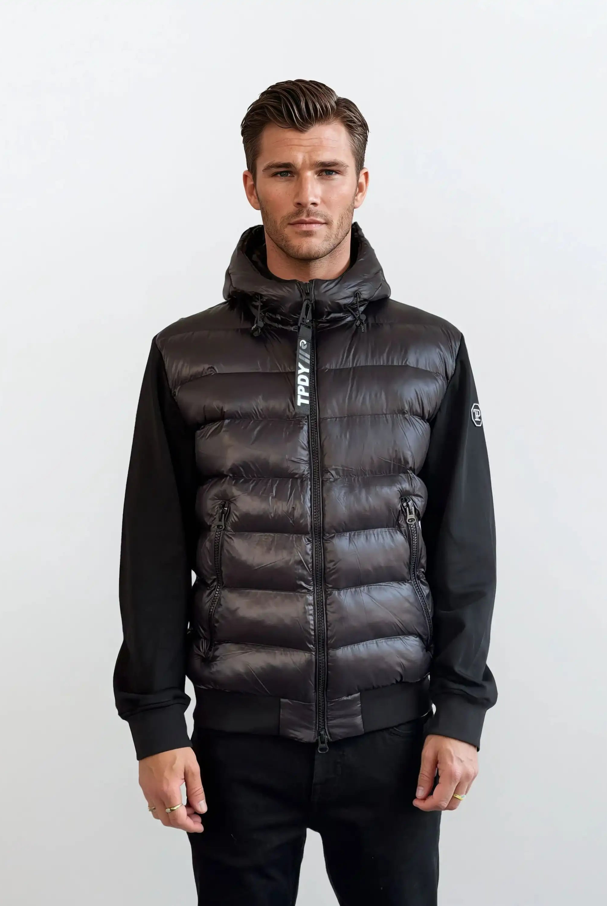 Ein Mann mit kurzen braunen Haaren trägt die trueprodigy Gesteppte Herren Übergangsjacke für urbanen City-Style, mit einem Frontreißverschluss und langen Ärmeln. Er steht mit neutralem Gesichtsausdruck vor einem schlichten hellgrauen Hintergrund.