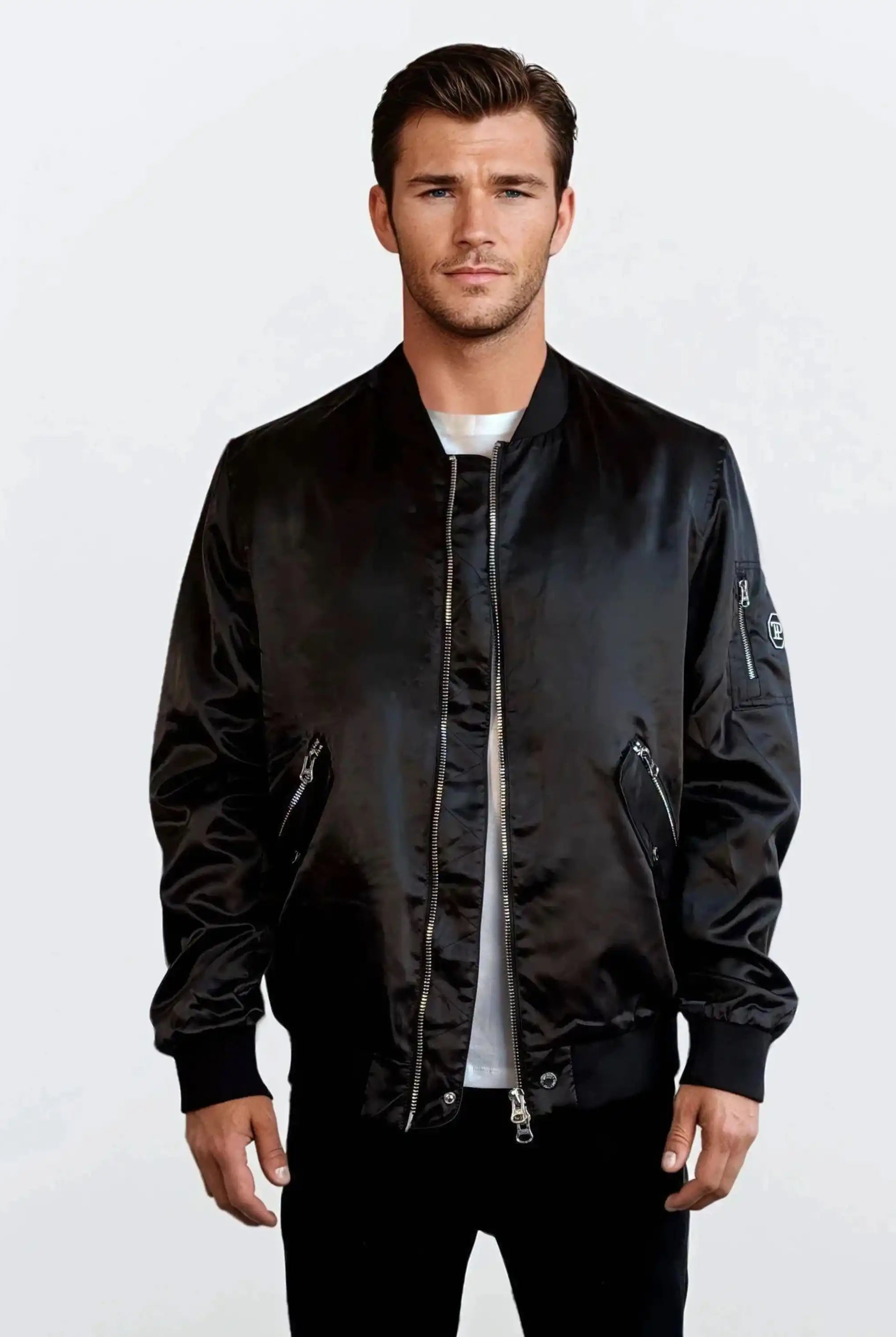 Ein Mann steht vor einem schlichten weißen Hintergrund und trägt eine trueprodigy Klassische Herren Bomberjacke mit glänzender Oberfläche über einem weißen T-Shirt. Die Jacke hat Reißverschlusstaschen, gerippte Bündchen und einen gerippten Saum, was ihr einen urbanen Stil verleiht.