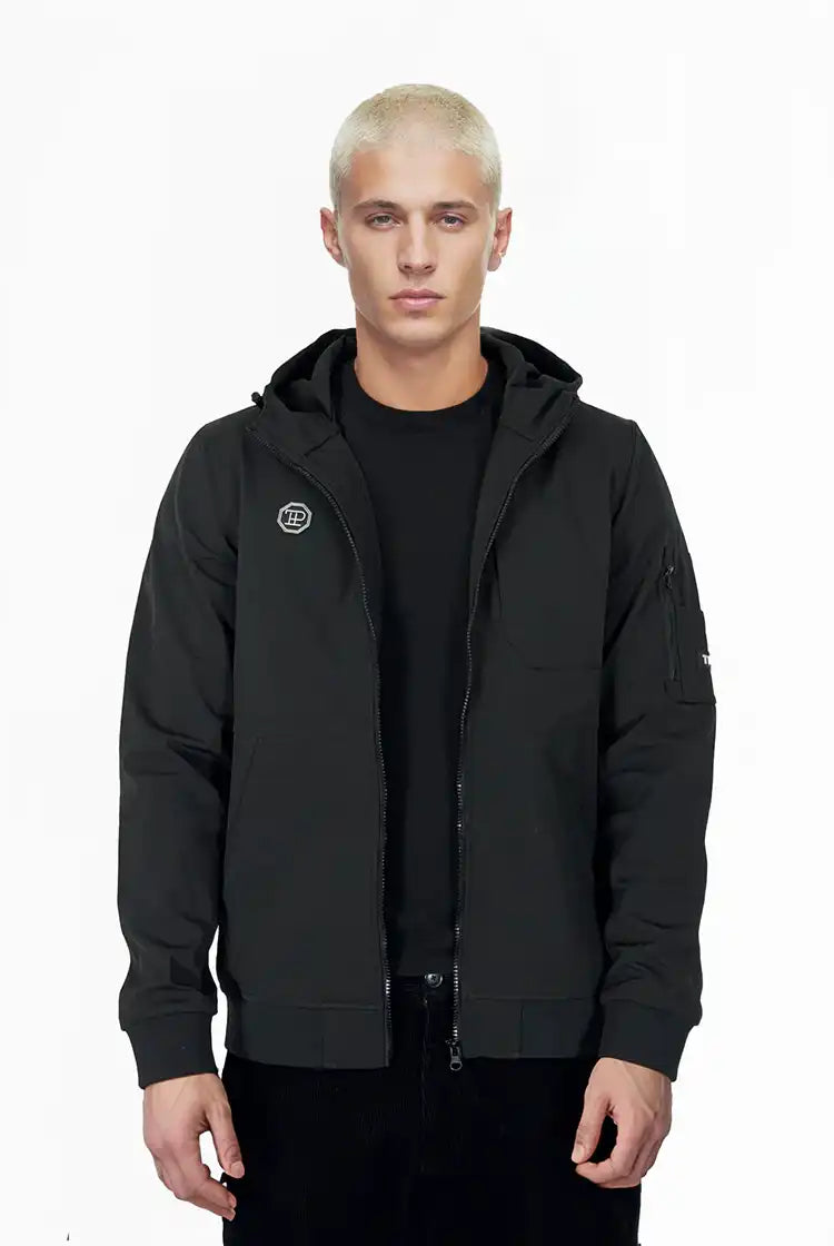 Eine Person mit kurzen, gebleichten blonden Haaren trägt die Trueprodigy Lucas Leichte Herrenjacke mit Brust- und Ärmelbadge und ein schwarzes T-Shirt vor einem schlichten weißen Hintergrund.