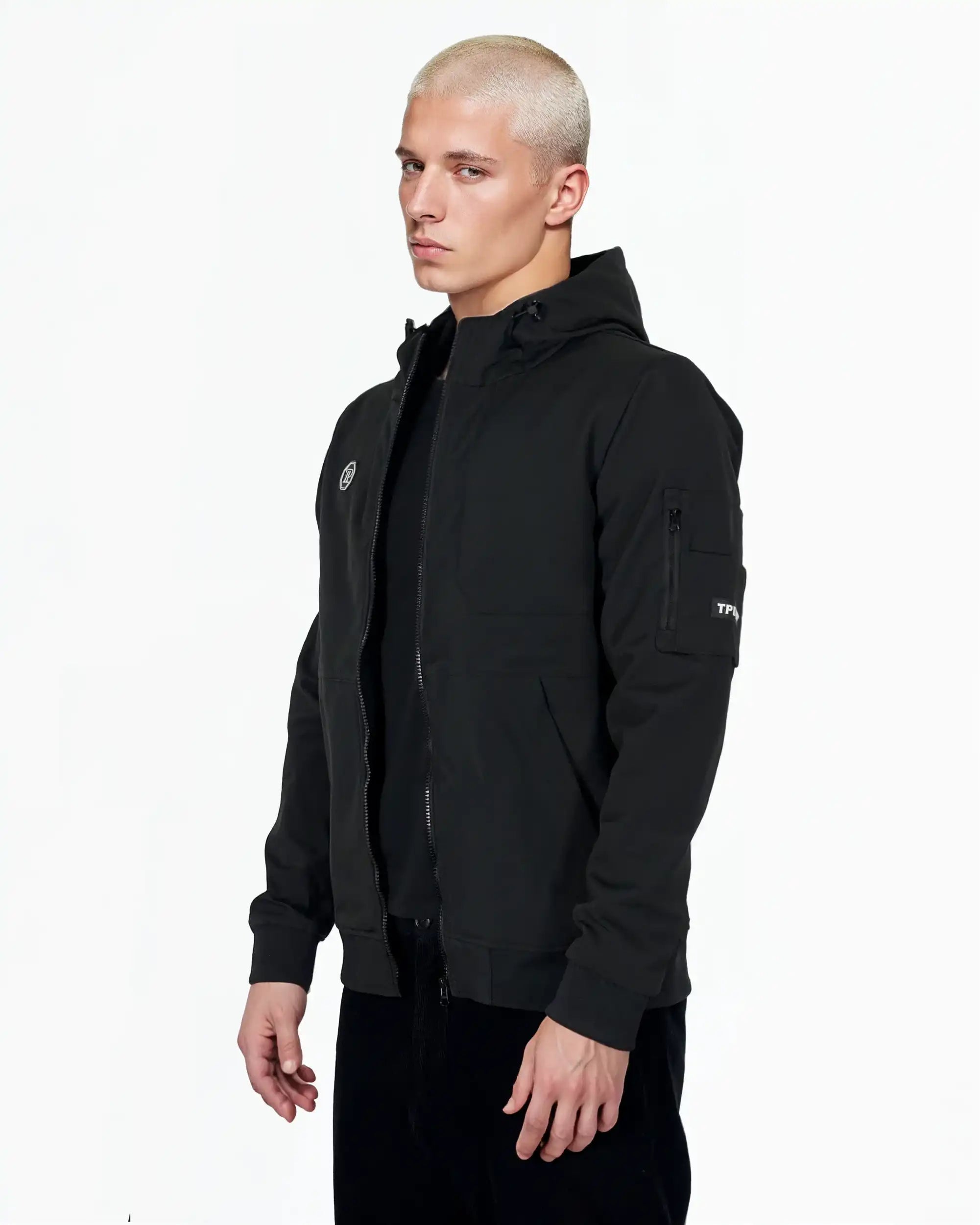 Eine Person mit kurzen, gebleichten blonden Haaren trägt das Lucas Leichte Herrenjacke mit Brust- und Ärmelbadge von trueprodigy mit einem Reißverschluss, zwei Brusttaschen und einem Ärmelaufnäher vor einem schlichten weißen Hintergrund.