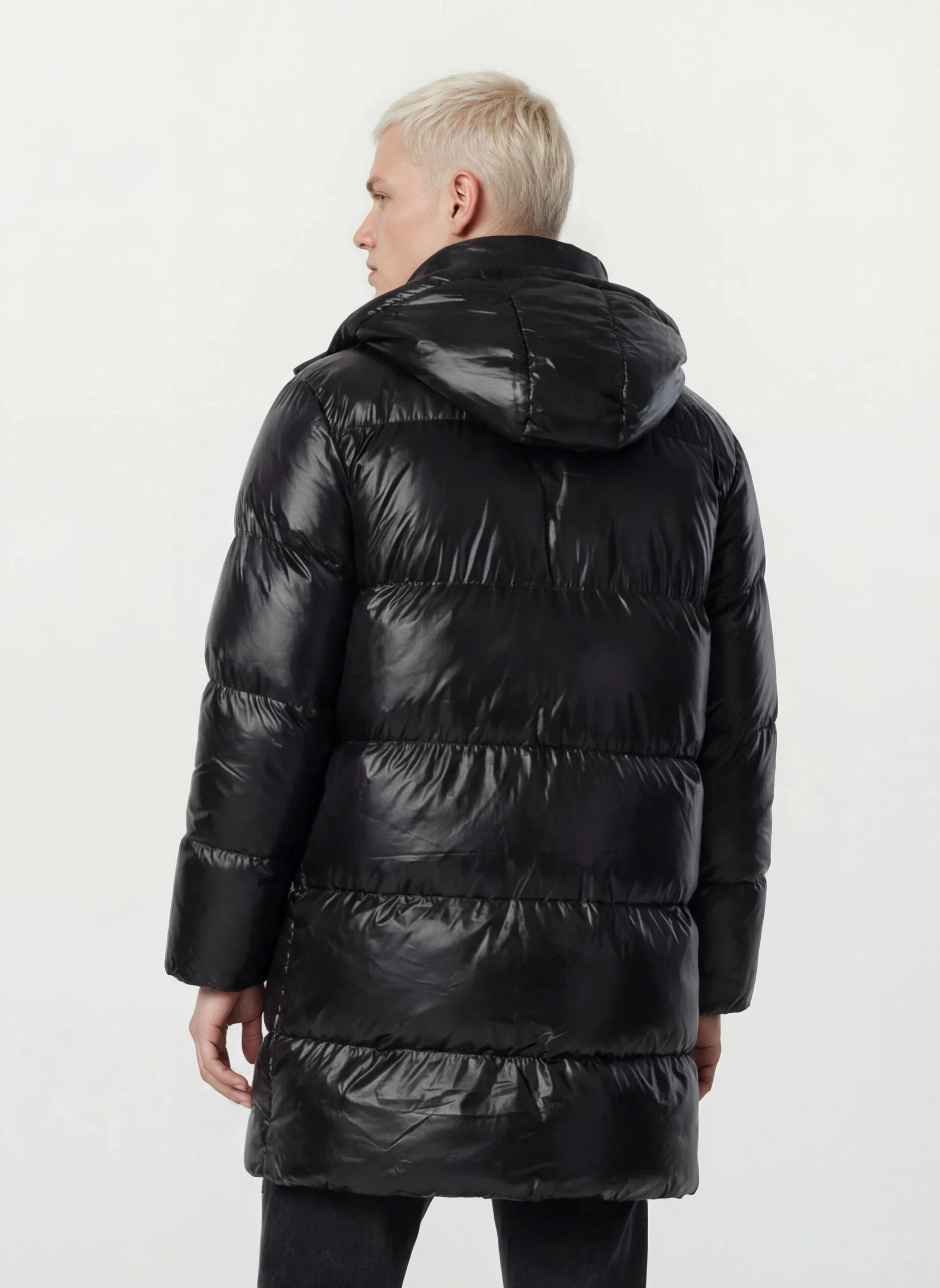 Eine Person mit kurzen blonden Haaren trägt eine trueprodigy Herren Winterjacke mit hochglänzender Oberfläche im Regular Fit, von der Kamera abgewandt vor einem schlichten weißen Hintergrund.