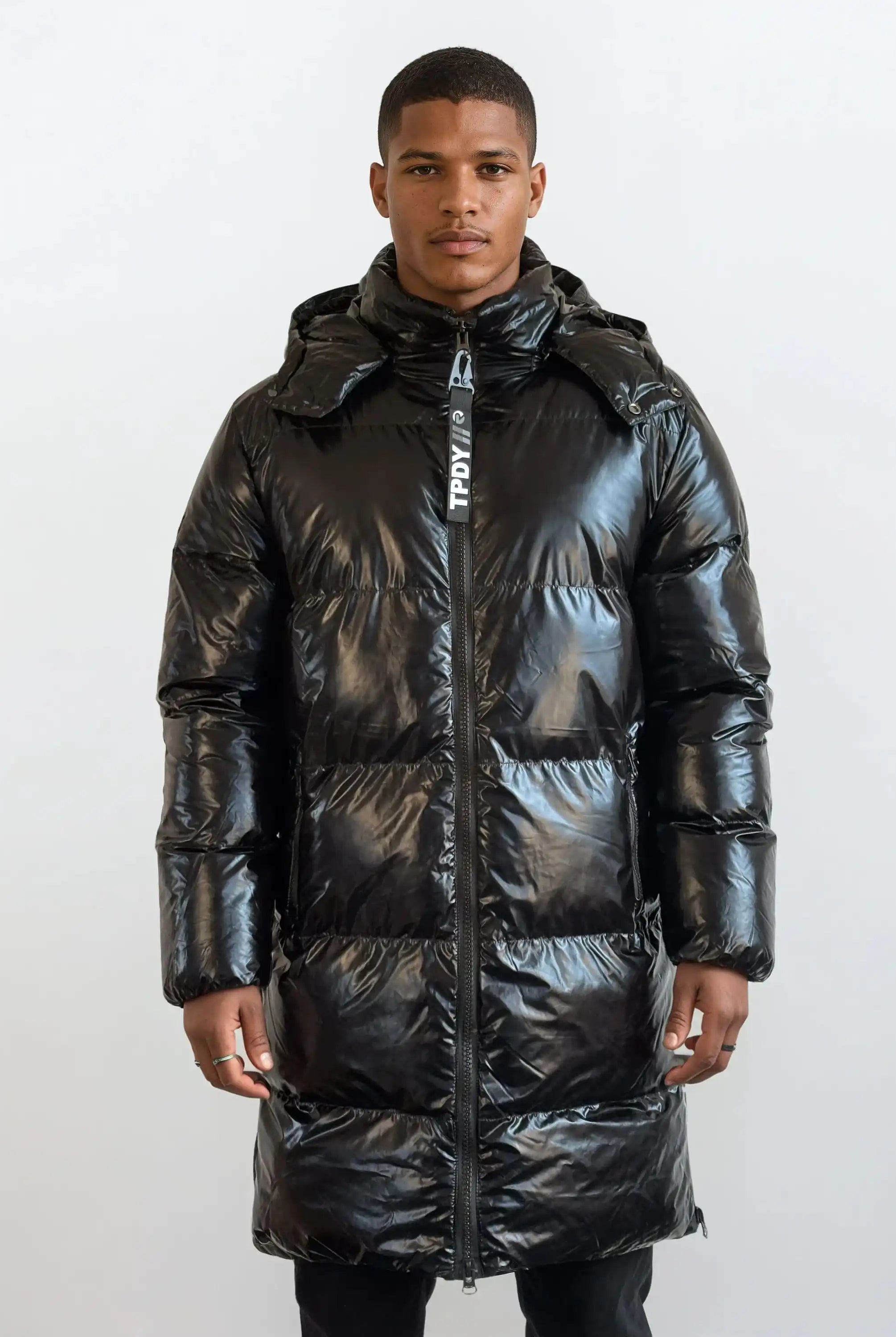 Eine Person steht mit Blick nach vorne in einer trueprodigy Herren Winterjacke mit hochglänzender Oberfläche im Regular Fit, mit Kapuze und sichtbarem Reißverschluss, vor einem schlichten hellen Hintergrund.