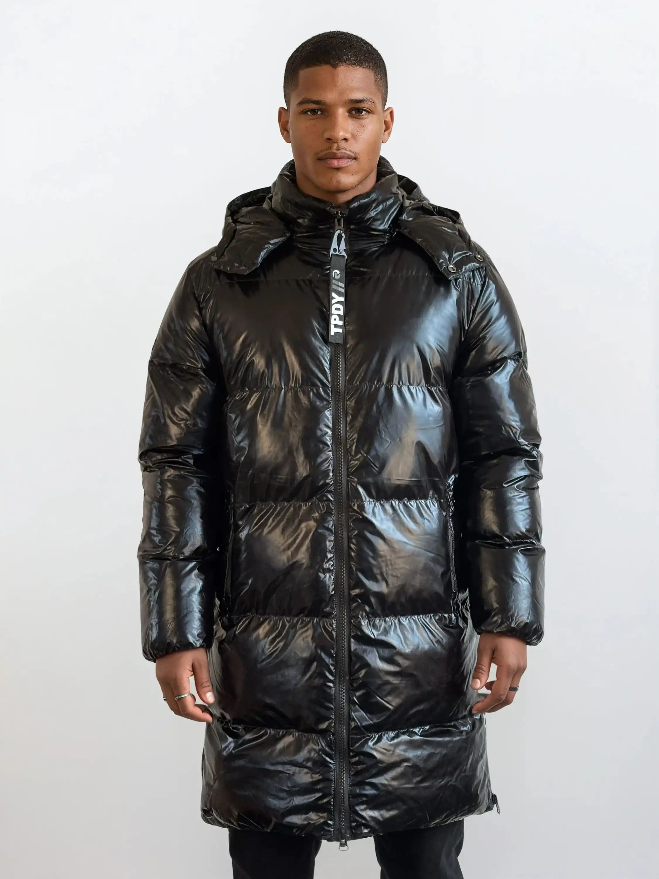 Eine Person steht mit Blick nach vorne in einer trueprodigy Herren Winterjacke mit hochglänzender Oberfläche im Regular Fit, mit Kapuze und sichtbarem Reißverschluss, vor einem schlichten hellen Hintergrund.