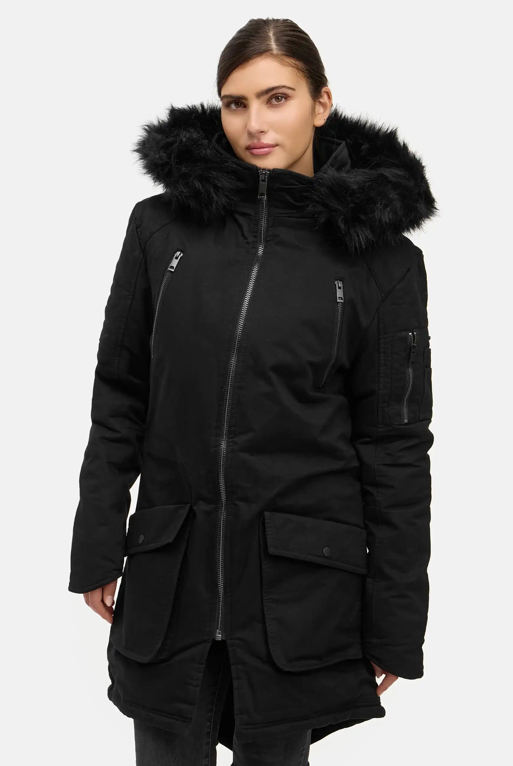 Eine Frau, die den trueprodigy Harvey F Damenparka mit Kapuze und Kunstfell in Schwarz mit Frontreißverschluss, seitlichen Pattentaschen und Brusttaschen mit Reißverschluss trägt, steht mit nach vorne gezogenem, glattem braunem Haar.