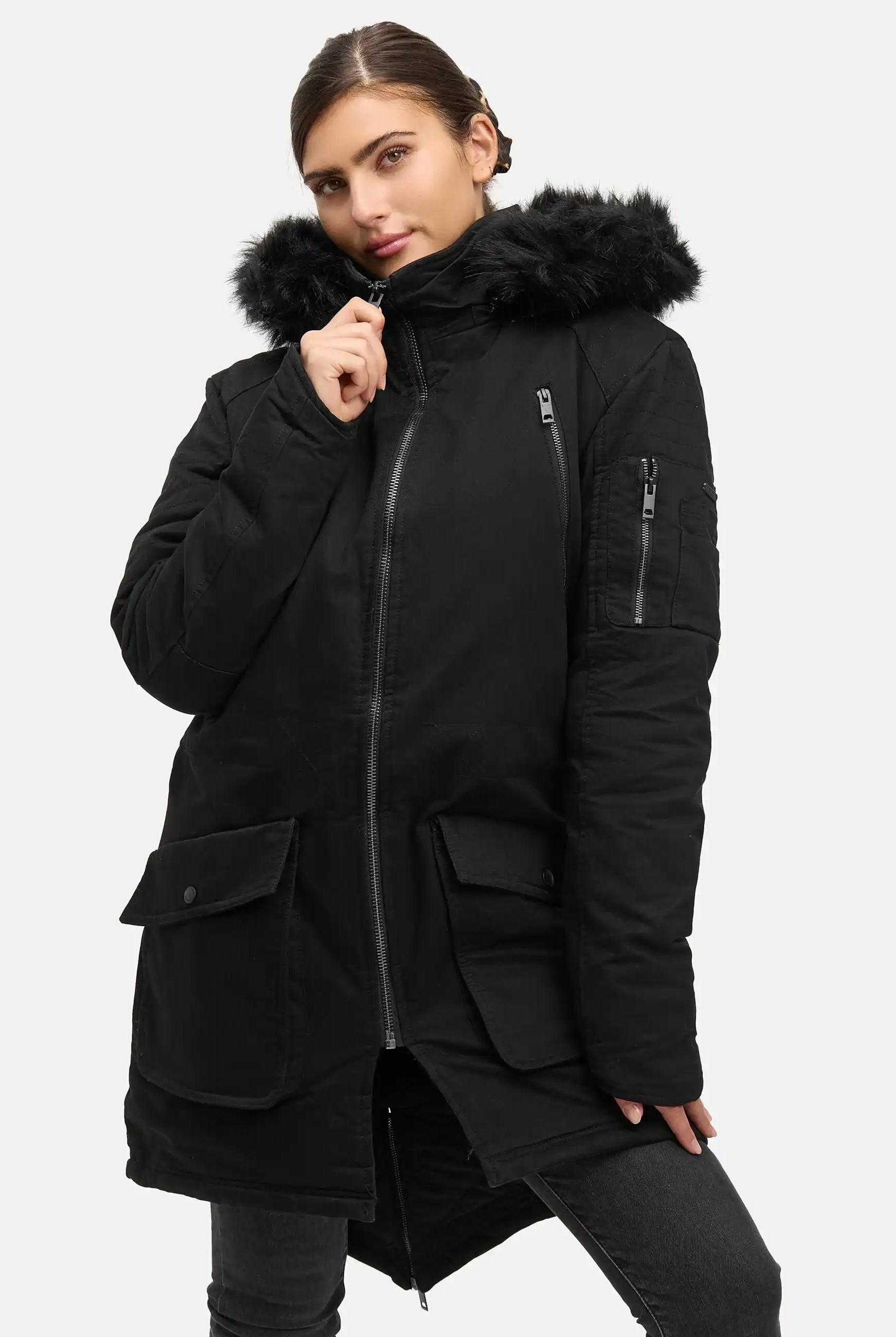 Eine Person trägt den trueprodigy Harvey F Damenparka mit Kapuze und Kunstfell, mit mehreren Reißverschluss- und Pattentaschen und einem Reißverschluss auf der Vorderseite, vor einem schlichten, hellen Hintergrund.