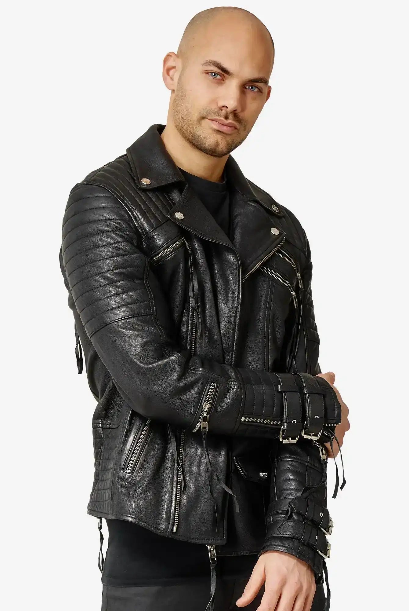 Ein Mann mit neutralem Gesichtsausdruck steht vor einem unifarbenen Hintergrund, die Arme locker verschränkt, und trägt die trueprodigy Jackson Bikerlederjacke mit Schnallen, gesteppten Ärmeln und Reißverschlusstaschen.