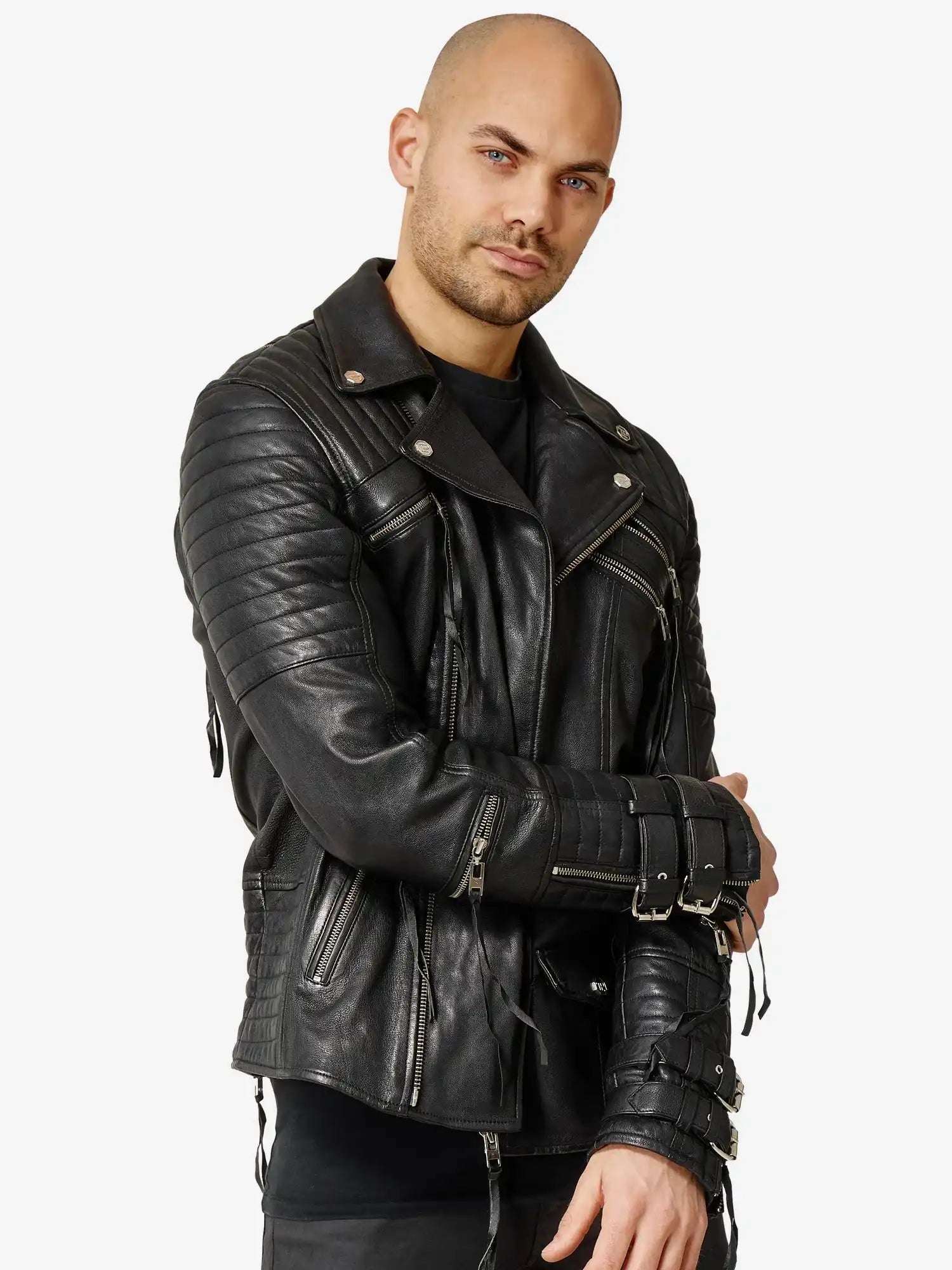 Ein Mann mit neutralem Gesichtsausdruck steht vor einem unifarbenen Hintergrund, die Arme locker verschränkt, und trägt die trueprodigy Jackson Bikerlederjacke mit Schnallen, gesteppten Ärmeln und Reißverschlusstaschen.