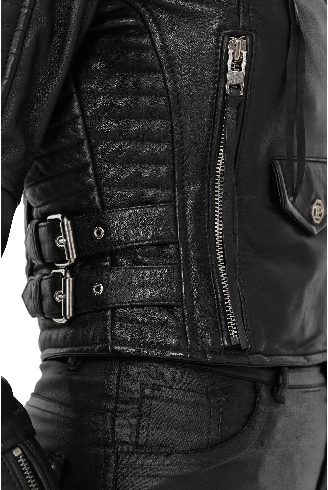 Nahaufnahme einer Person, die die trueprodigy Freya Bikerlederjacke mit Schnallen trägt, mit gesteppten Details, vertikaler Reißverschlusstasche, seitlichen Schnallenriemen, gepaart mit einer schwarzen Lederhose für einen authentischen Biker-Look.