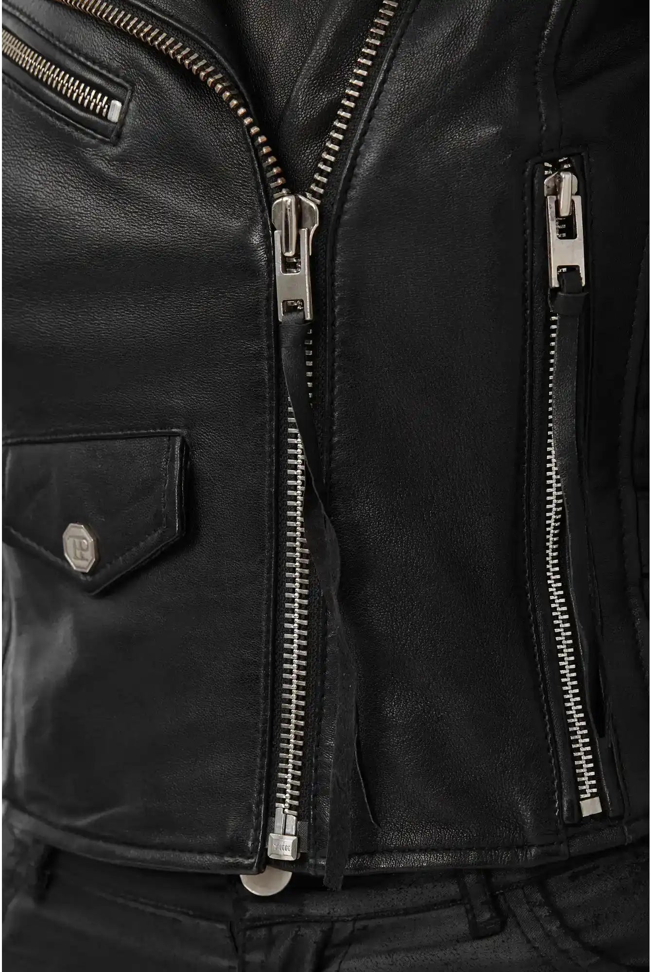 Nahaufnahme der trueprodigy Freya Bikerlederjacke mit Schnallen in schwarzem Schafsleder mit silbernen Reißverschlüssen und kleiner Klappentasche, detailreiche Nähte und Textur. Der klassische Biker-Look passt ideal zu schwarzen Hosen.