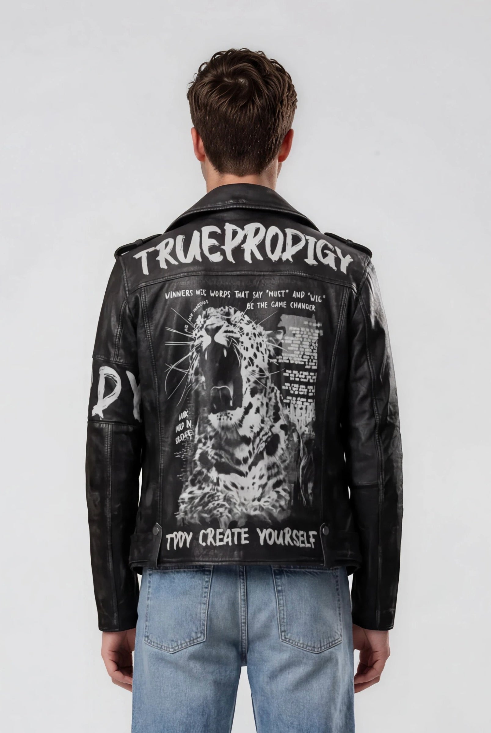 Eine Person in hellblauen Jeans und einer schwarzen Trueprodigy Biker Lederjacke Herren "Russell" mit Rücken-Print - mit Text und einer rasanten Leopardengrafik - zeigt einen gewagten Biker-Look, von hinten gesehen vor einem schlichten, hellen Hintergrund.