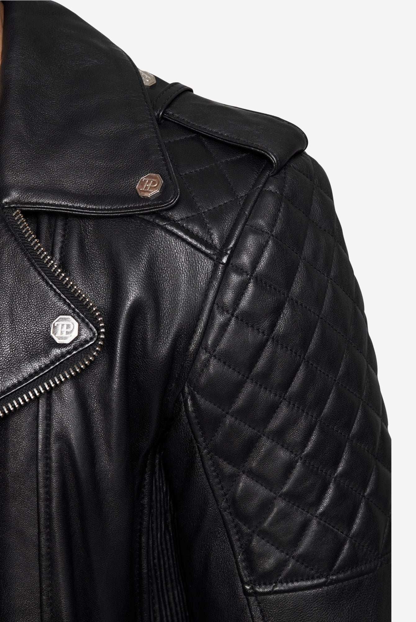 Nahaufnahme einer trueprodigy Simba Bikerlederjacke mit Gürtel, mit gesteppten Schulternähten, silbernen Druckknöpfen und einem sichtbaren Reißverschluss. Das Foto konzentriert sich auf die obere Brust und die Schulter des Trägers.