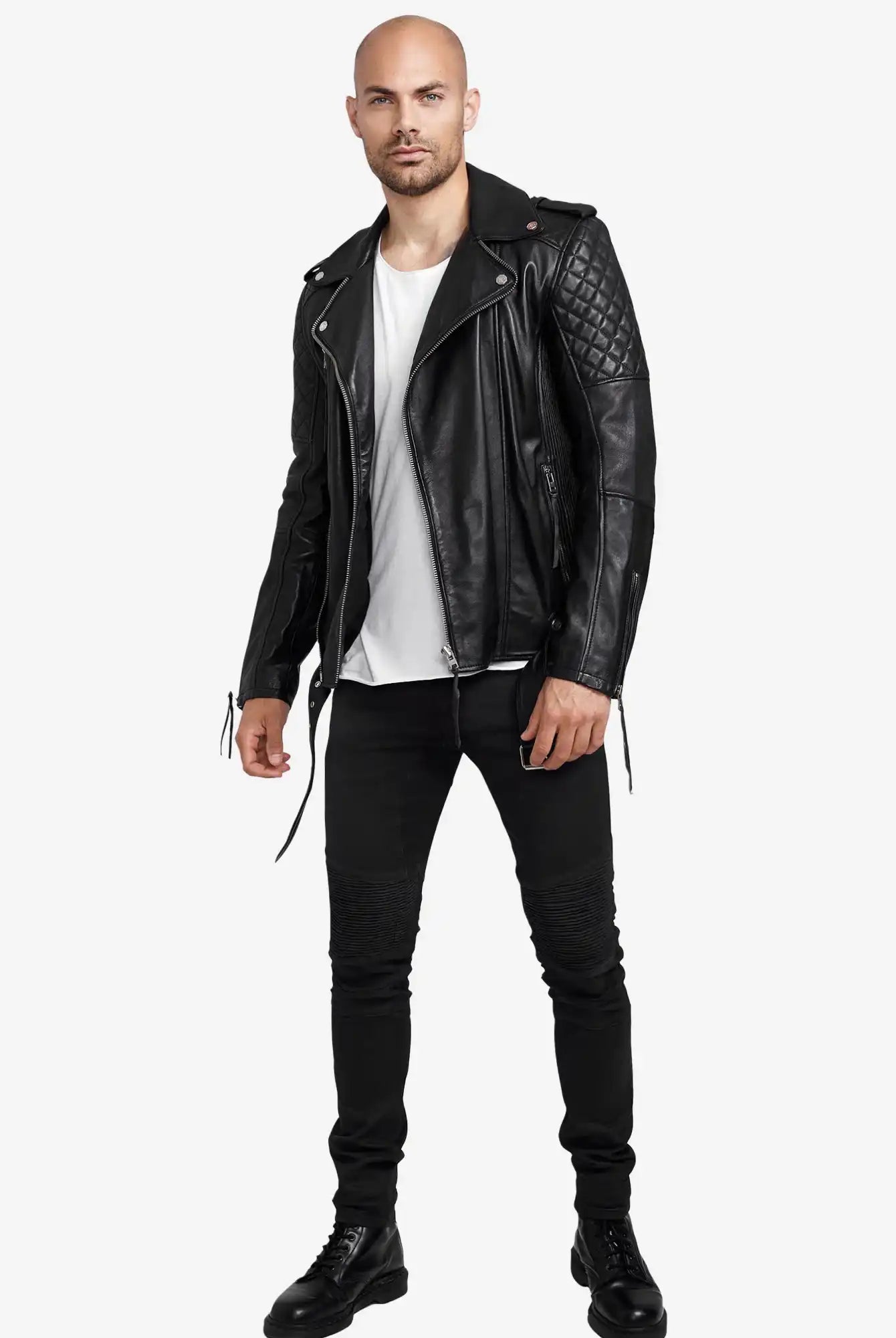 Ein Mann sieht nach vorne und trägt eine Trueprodigy Simba Bikerlederjacke mit Gürtel in Schwarz, ein weißes T-Shirt, eine schwarze Hose und schwarze Stiefel vor einem schlichten weißen Hintergrund.