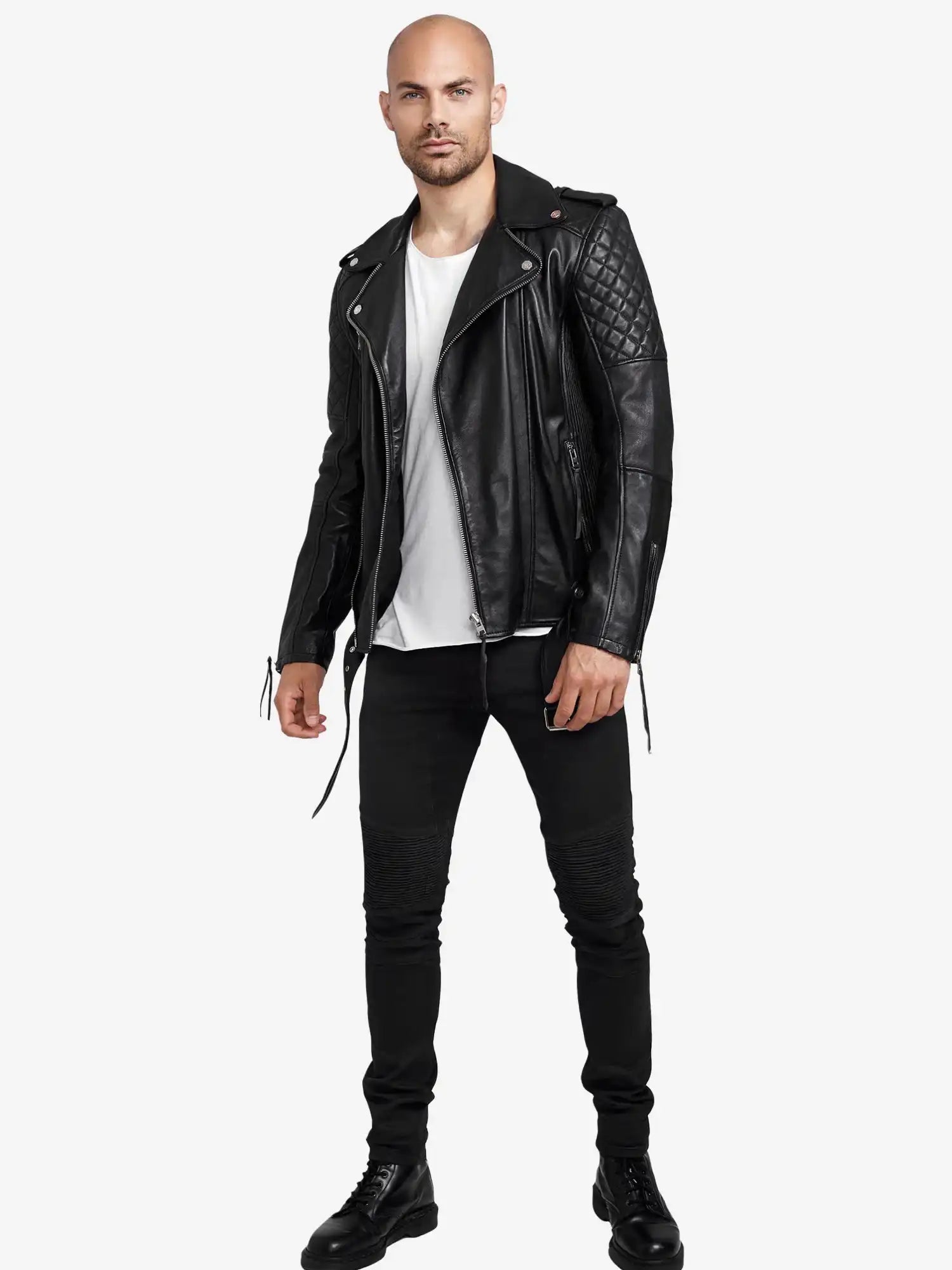 Ein Mann sieht nach vorne und trägt eine Trueprodigy Simba Bikerlederjacke mit Gürtel in Schwarz, ein weißes T-Shirt, eine schwarze Hose und schwarze Stiefel vor einem schlichten weißen Hintergrund.