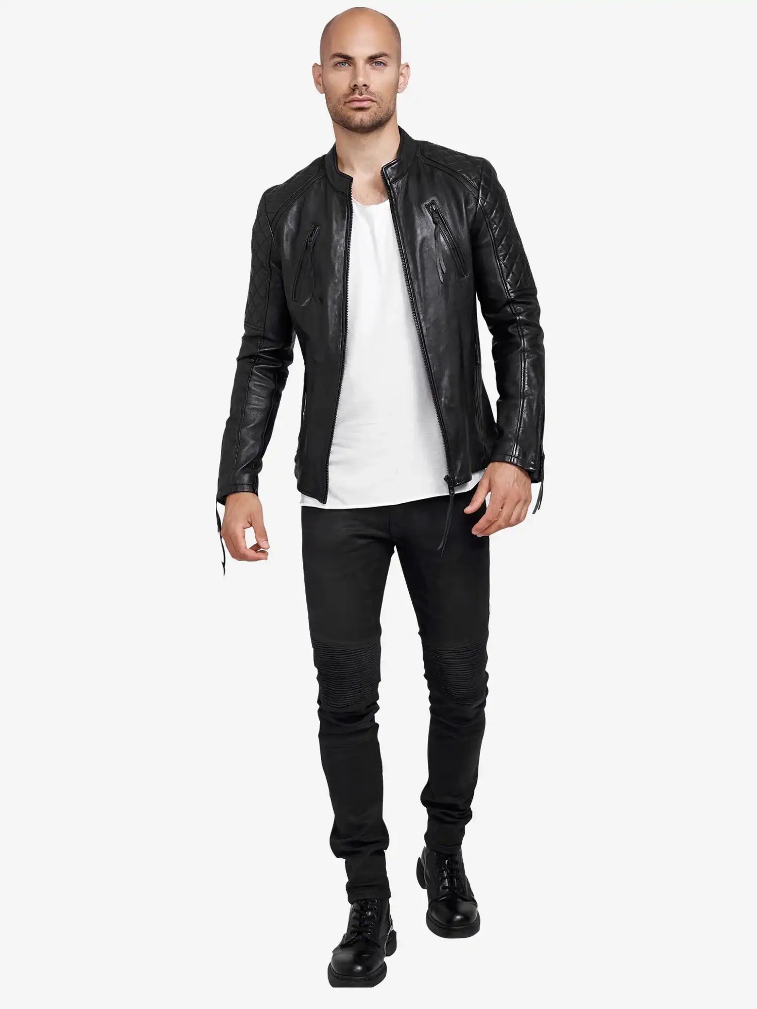 Ein Mann steht frontal, trägt die trueprodigy Franky Lederjacke mit Stehkragen, ein weißes T-Shirt, schwarze Jeans und Boots. Er ist kahlköpfig, hat kurzen Bart und einen neutralen Gesichtsausdruck mit leicht erhobener Hand.