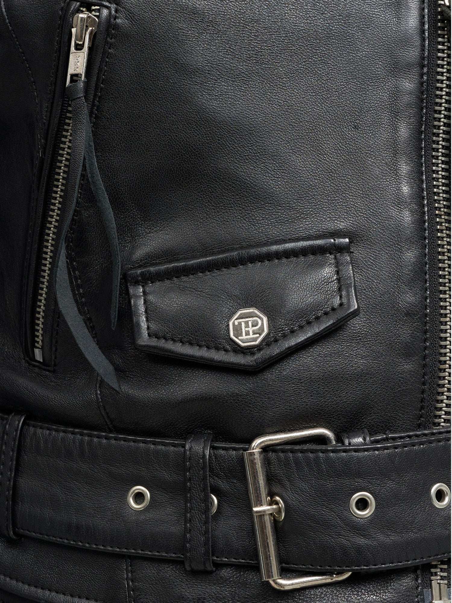 Nahaufnahme der trueprodigy Laila Lederjacke mit Druck, die mit einer Reißverschlusstasche, einer kleinen Pattentasche mit silbernem Emblem und einem passenden Ledergürtel ausgestattet ist - ideal für einen ausgefallenen Trend-Look.