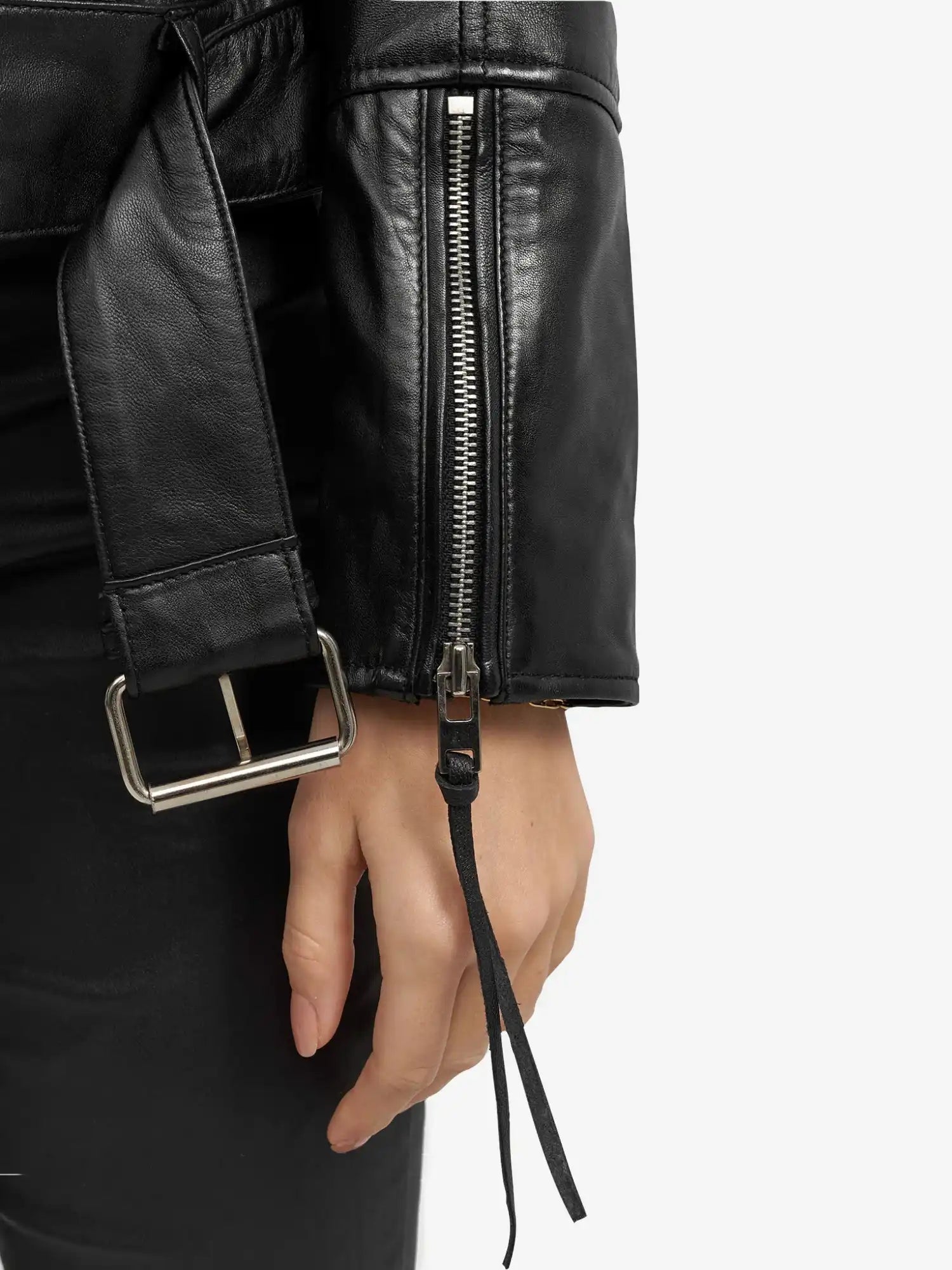 Nahaufnahme einer seitlich ruhenden Hand, die die trueprodigy Milena Lederjacke mit Gürtel trägt - schwarzes Leder mit silbernem Ärmelreißverschluss und schwarzem Gürtel mit silberner Schnalle. Der Hintergrund ist einfarbig und hell gefärbt.