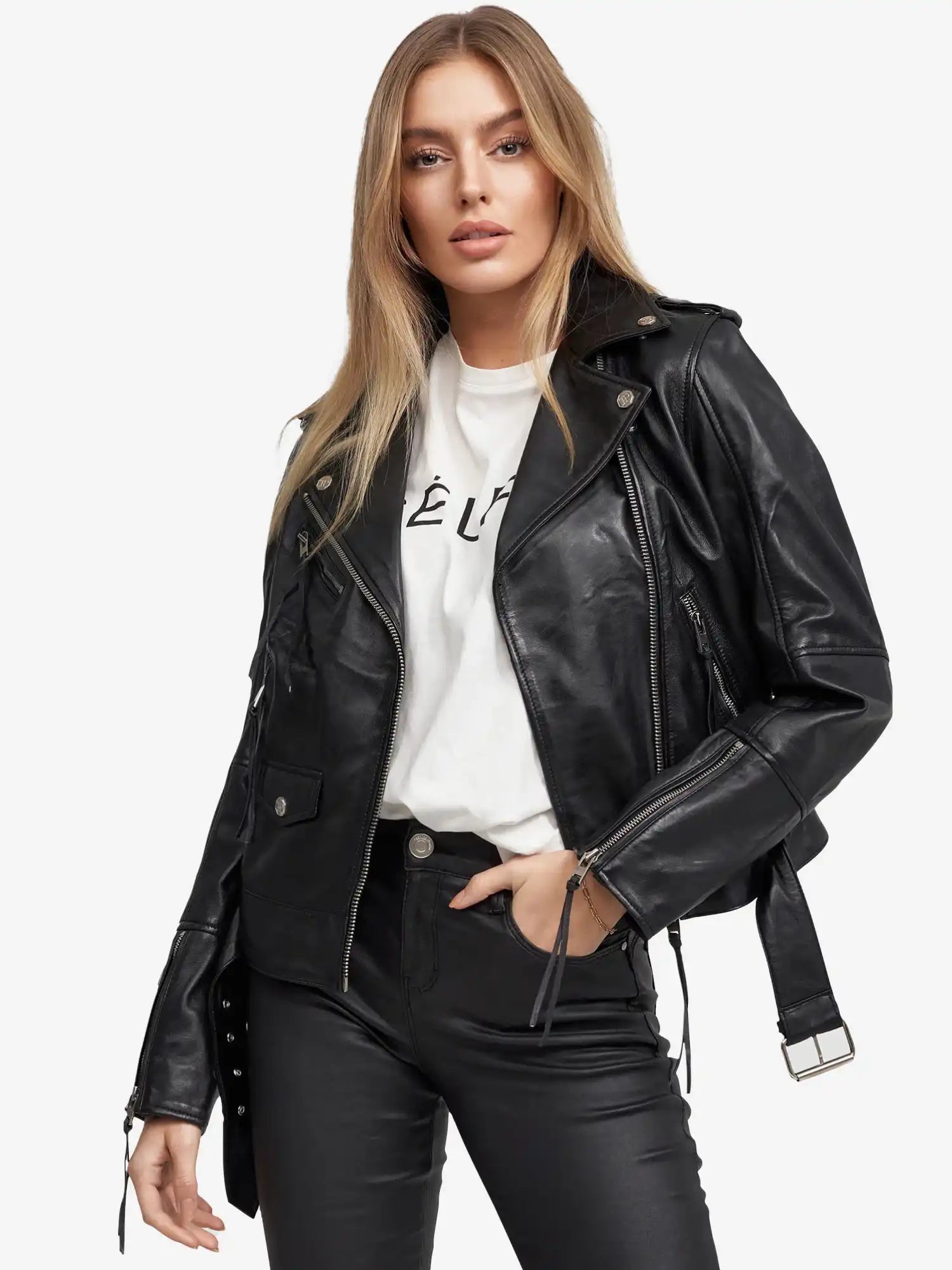 Eine Frau mit langen blonden Haaren trägt die trueprodigy Milena Lederjacke mit Gürtel-eine schwarze Damen-Lederjacke-über einem weißen T-Shirt mit schwarzem Text und schwarzen Hosen vor weißem Hintergrund.