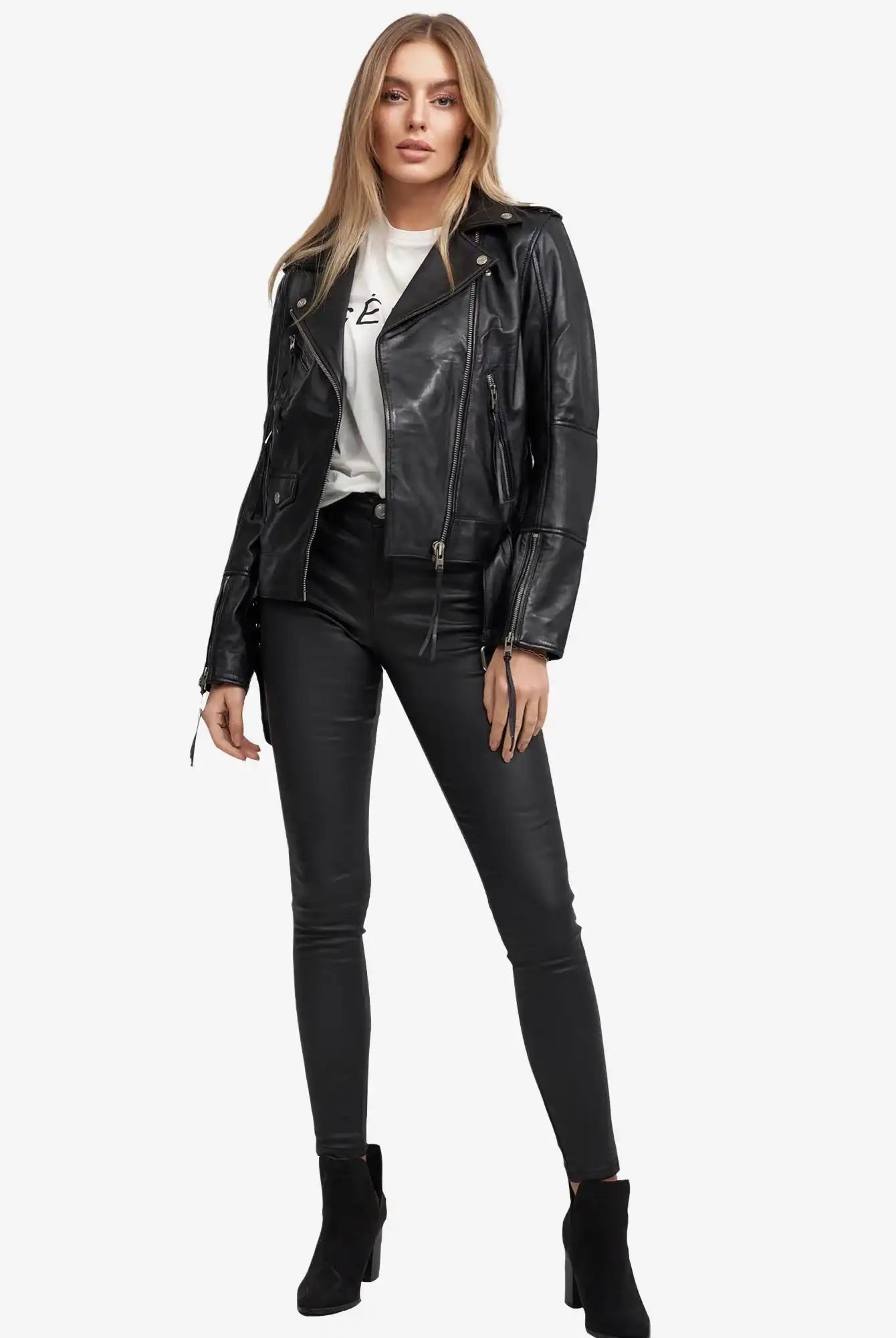 Eine Frau blickt nach vorne und trägt die Trueprodigy Milena Lederjacke mit Gürtel über einem weißen grafischen T-Shirt, gepaart mit einer schwarzen Skinny-Hose und Ankle Boots, vor einem schlichten weißen Hintergrund.