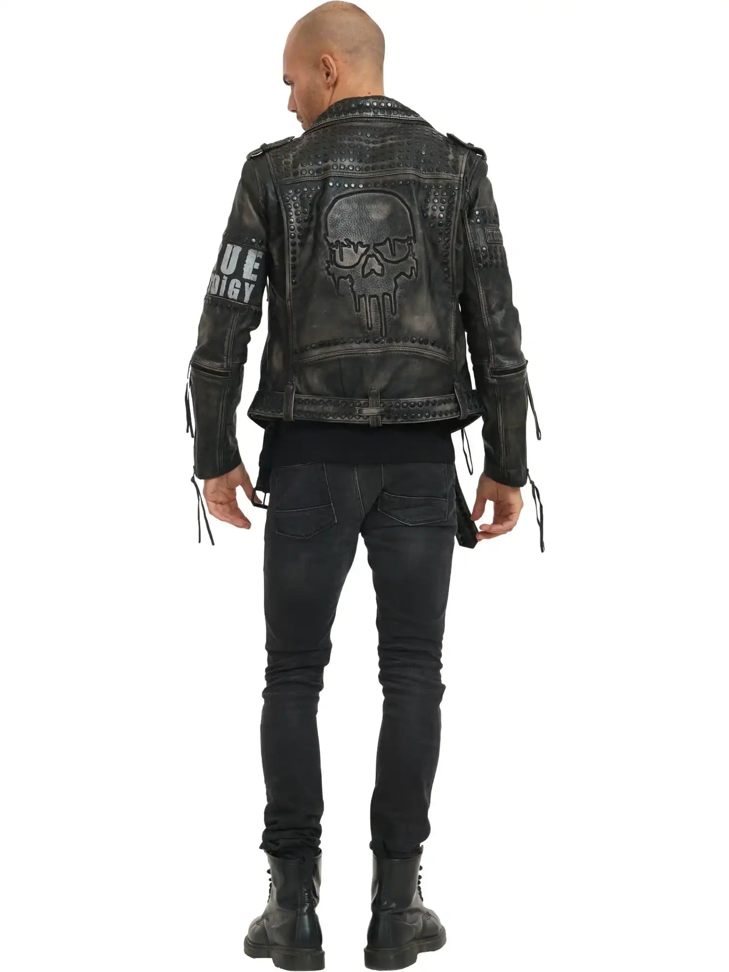Eine Person steht mit dem Gesicht zur Wand und trägt die trueprodigy Dwayne Lederjacke mit Nieten und Druck im Biker-Look, mit großem Totenkopf-Print auf dem Rücken, Nieten und Ärmelreißverschlüssen, gepaart mit schwarzen Jeans und Stiefeln. Textdetails akzentuieren die kantige Jacke.