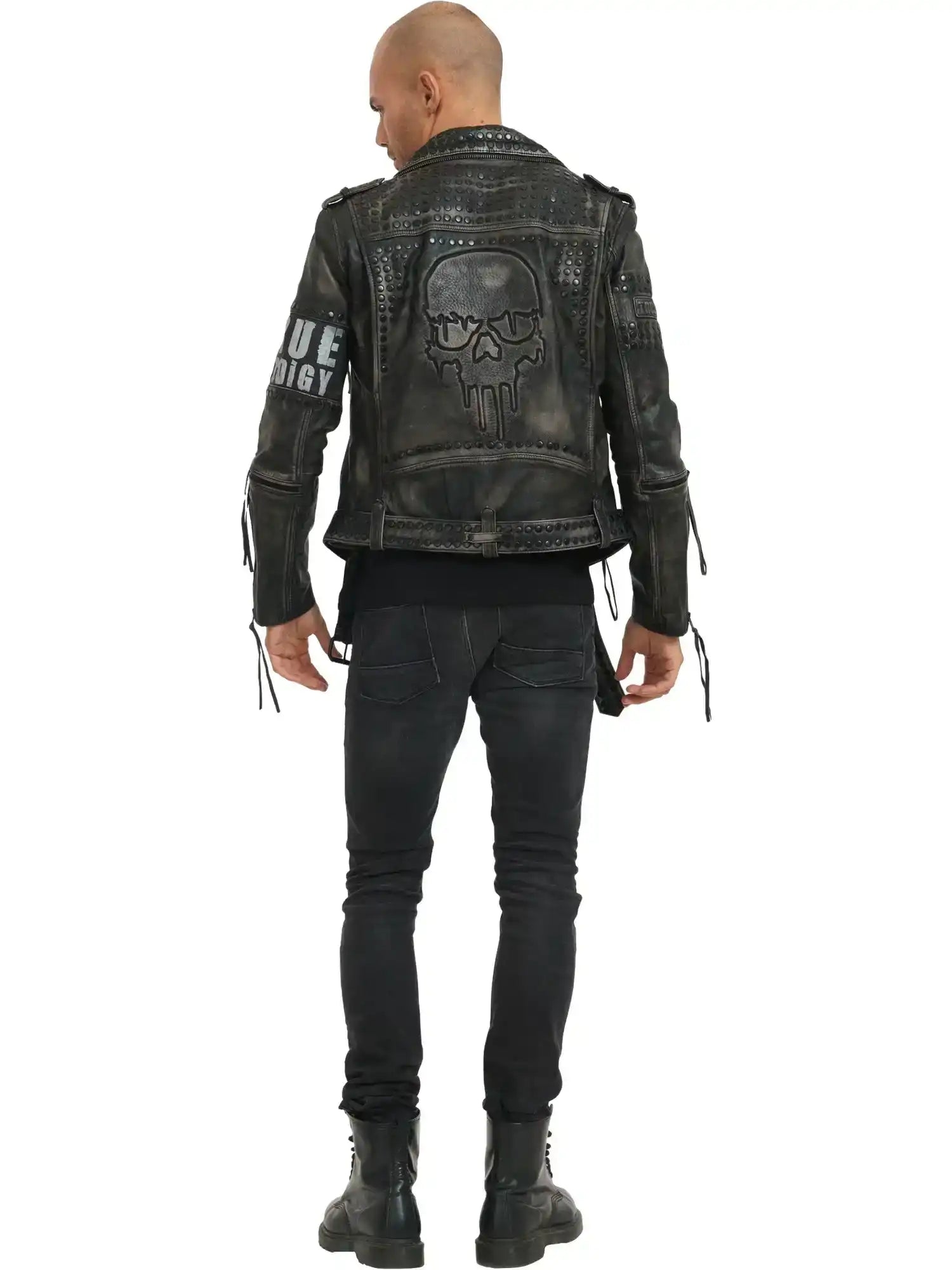Eine Person steht mit dem Gesicht zur Wand und trägt die trueprodigy Dwayne Lederjacke mit Nieten und Druck im Biker-Look, mit großem Totenkopf-Print auf dem Rücken, Nieten und Ärmelreißverschlüssen, gepaart mit schwarzen Jeans und Stiefeln. Textdetails akzentuieren die kantige Jacke.