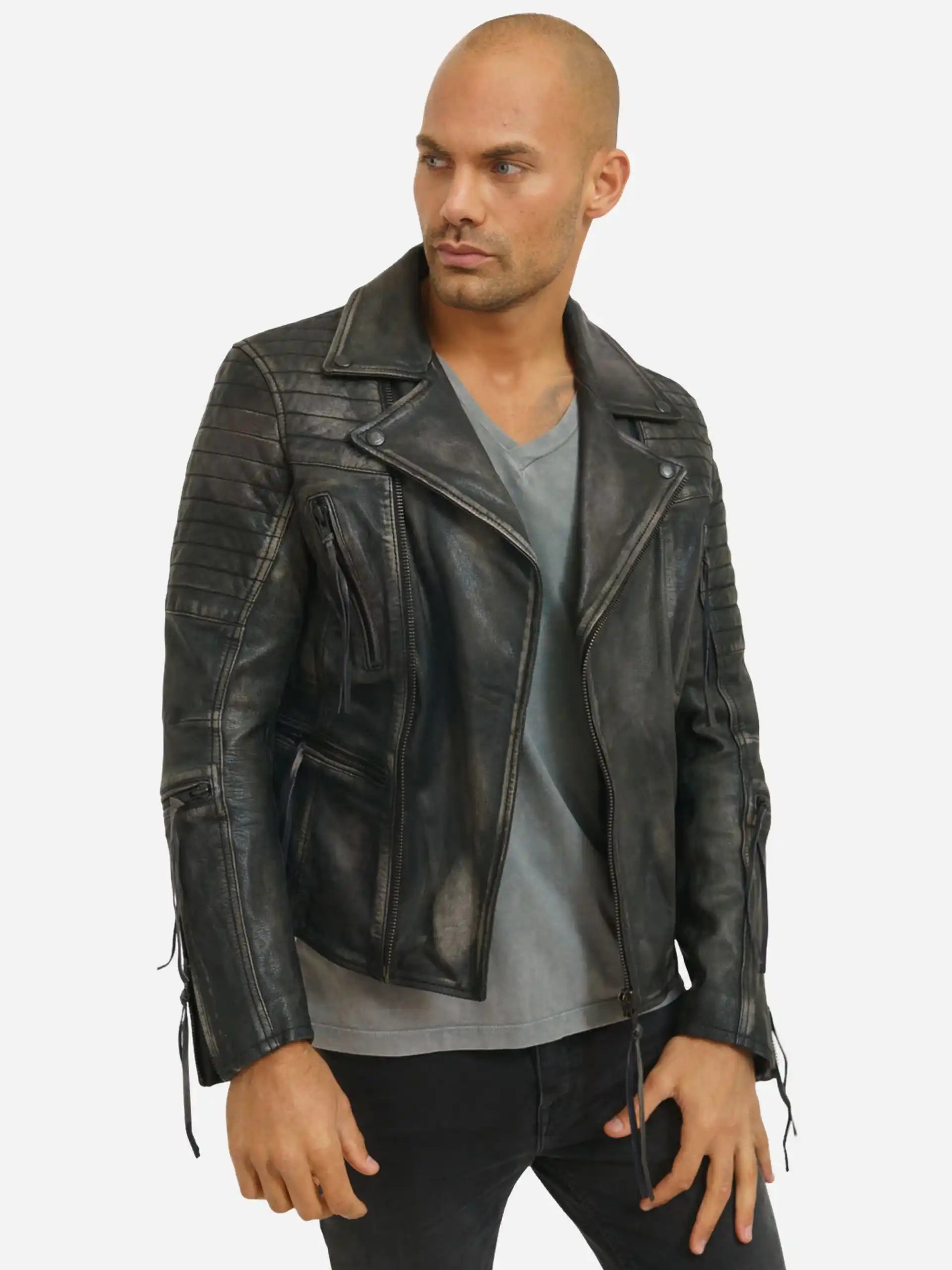 Eine Person steht leicht seitlich und trägt die trueprodigy Bryan Lederjacke mit Vintage Optik über einem grauen T-Shirt und einer schwarzen Hose. Die Jacke verfügt über Reißverschlusstaschen, gesteppte Schultern und geschnürte Manschetten. Der Hintergrund ist einfarbig weiß.