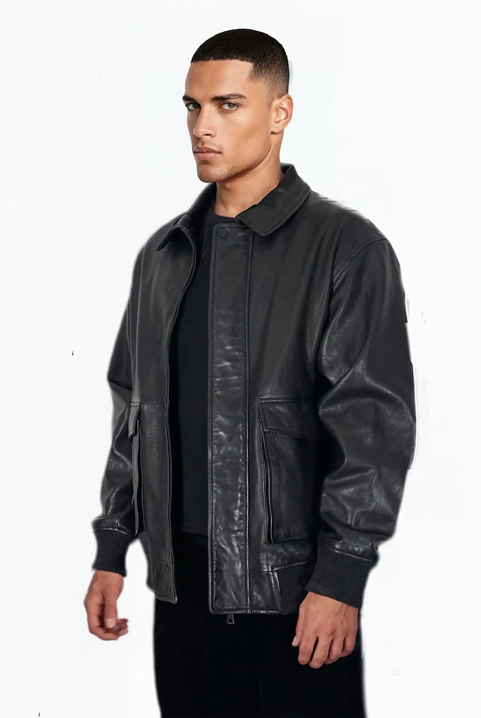 Ein Mann mit kurzen Haaren trägt die trueprodigy Ryder Oversize-Lederjacke mit Stehkragen, 3D-Silikonlogo & Retro-Details über einem schwarzen Hemd und einer Hose und steht leicht nach rechts gedreht vor einem schlichten weißen Hintergrund.