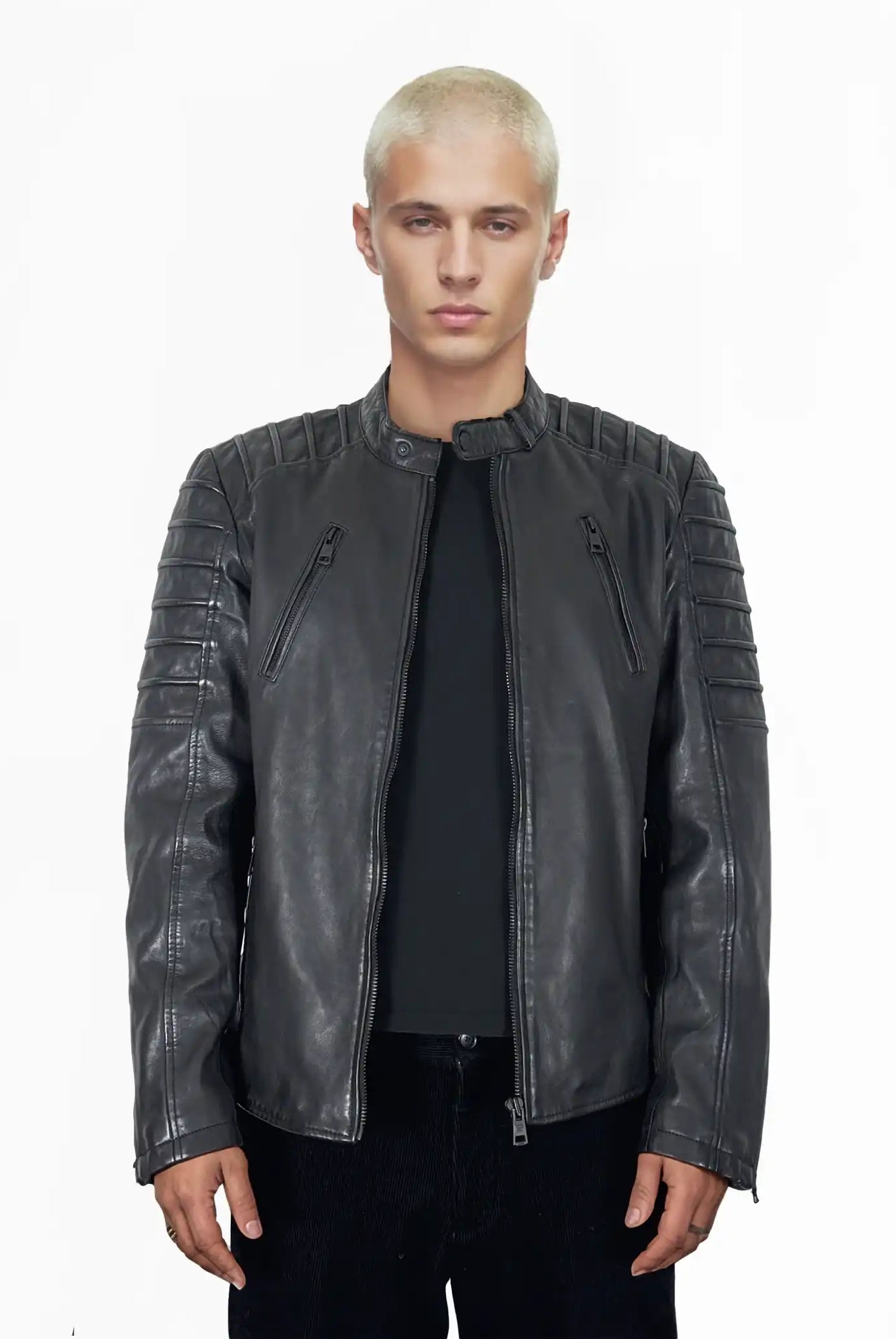 Eine Person mit kurzen blonden Haaren trägt die trueprodigy Dash Slim-Fit-Lederjacke mit Stehkragen & Zipper-Details über einem schwarzen Hemd und einer dunklen Hose, stehend vor einem schlichten weißen Hintergrund.