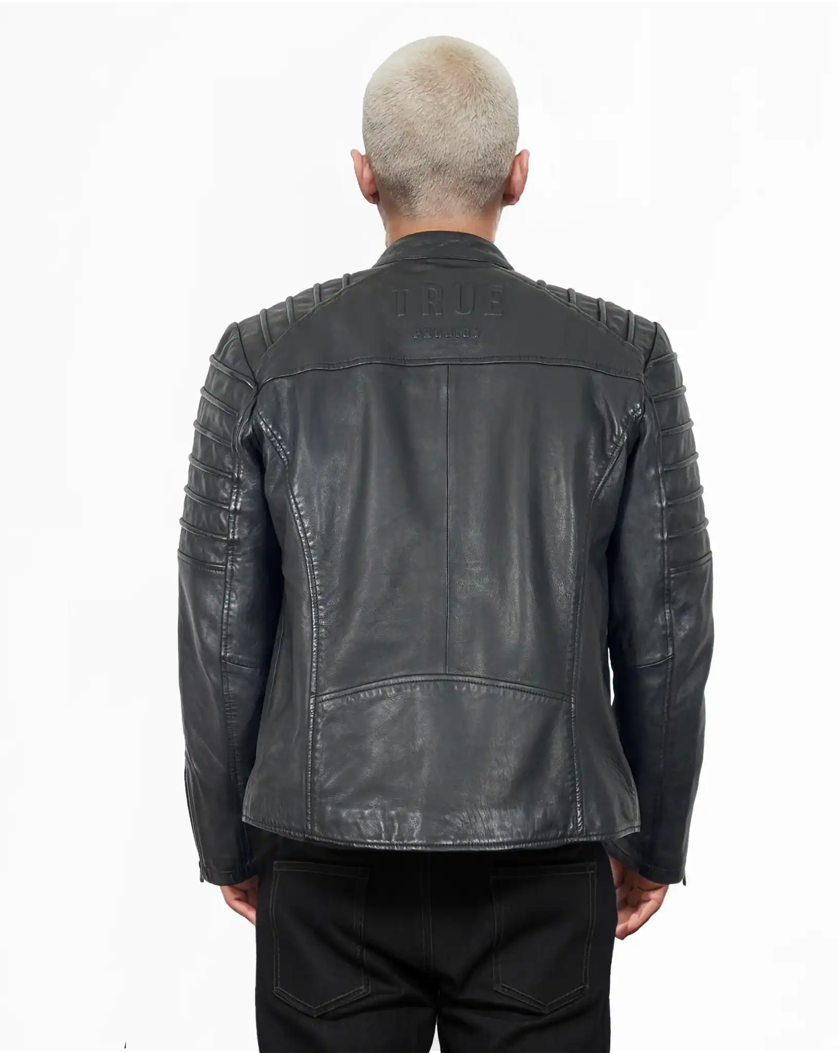 Eine Person mit kurzgeschnittenen, hellen Haaren trägt von hinten die schwarze Dash Slim-Fit-Lederjacke mit Stehkragen & Zipper-Details von trueprodigy, mit abgesteppten Schulter- und Armdetails und "TRUE"-Prägung auf dem oberen Rücken.