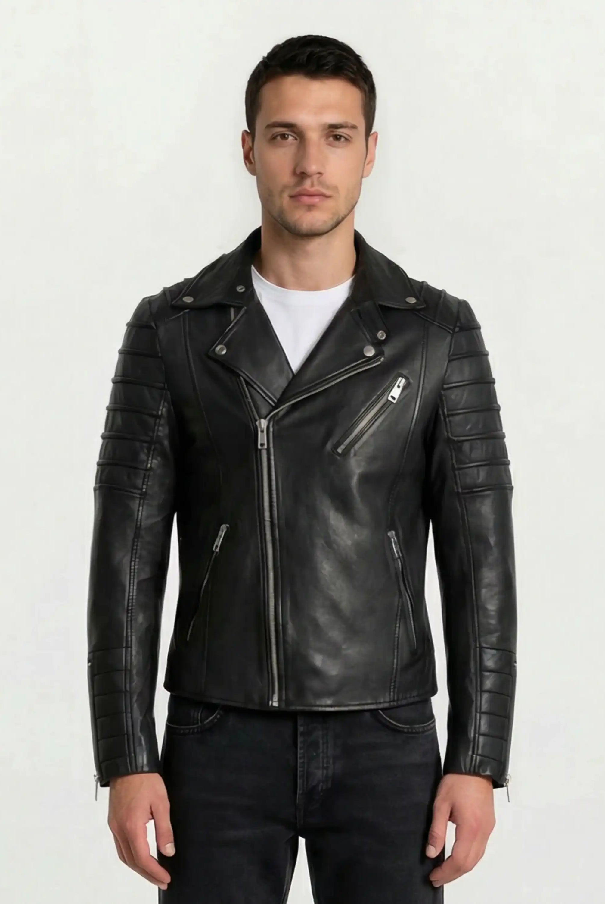 Ein Mann steht mit dem Gesicht nach vorne und trägt eine Trueprodigy Lederjacke mit Paspelierung und diversen Reißverschlüssen über einem weißen T-Shirt und schwarzen Jeans vor einem schlichten hellen Hintergrund.